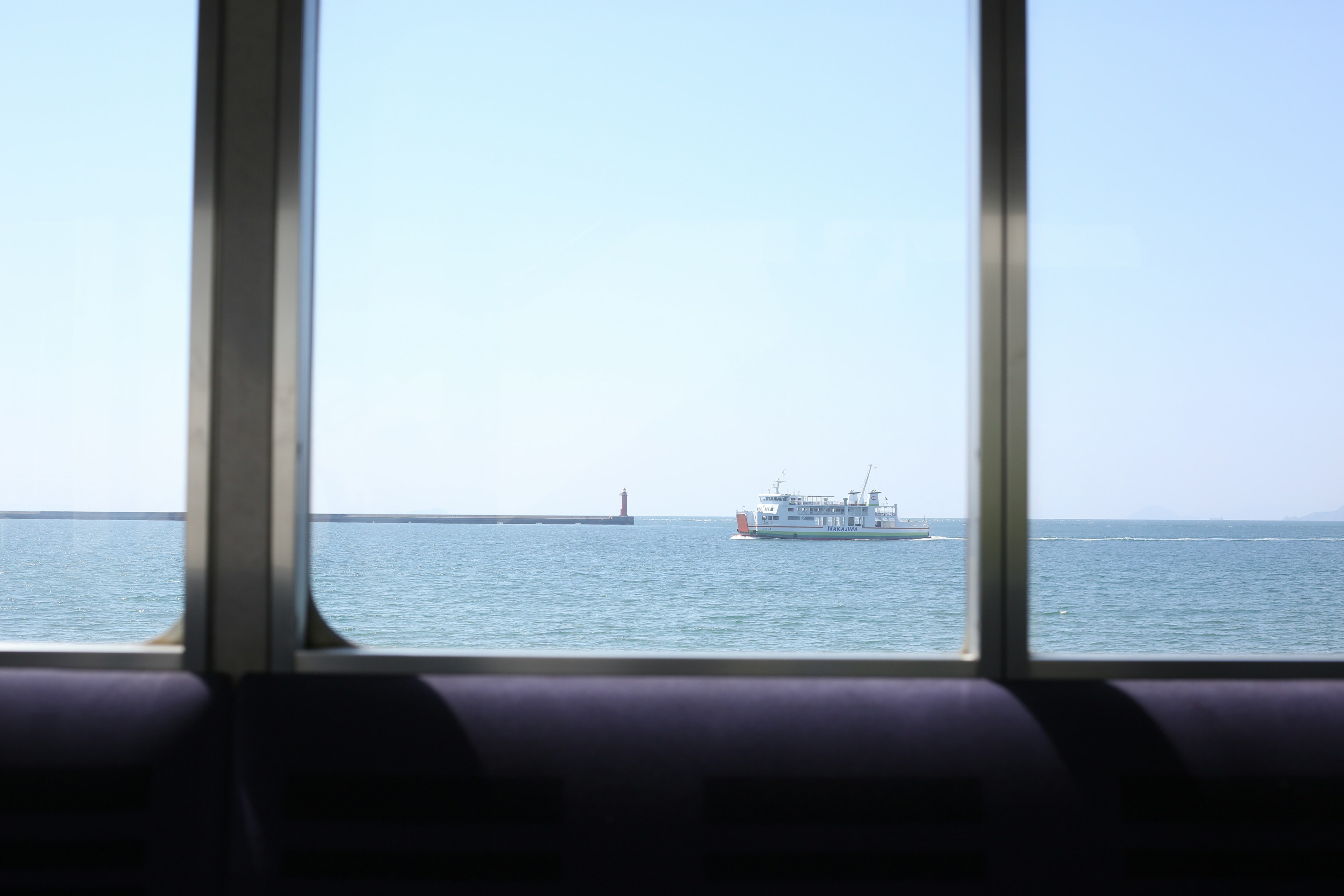 Vue sur la mer et un bateau à travers une fenêtre