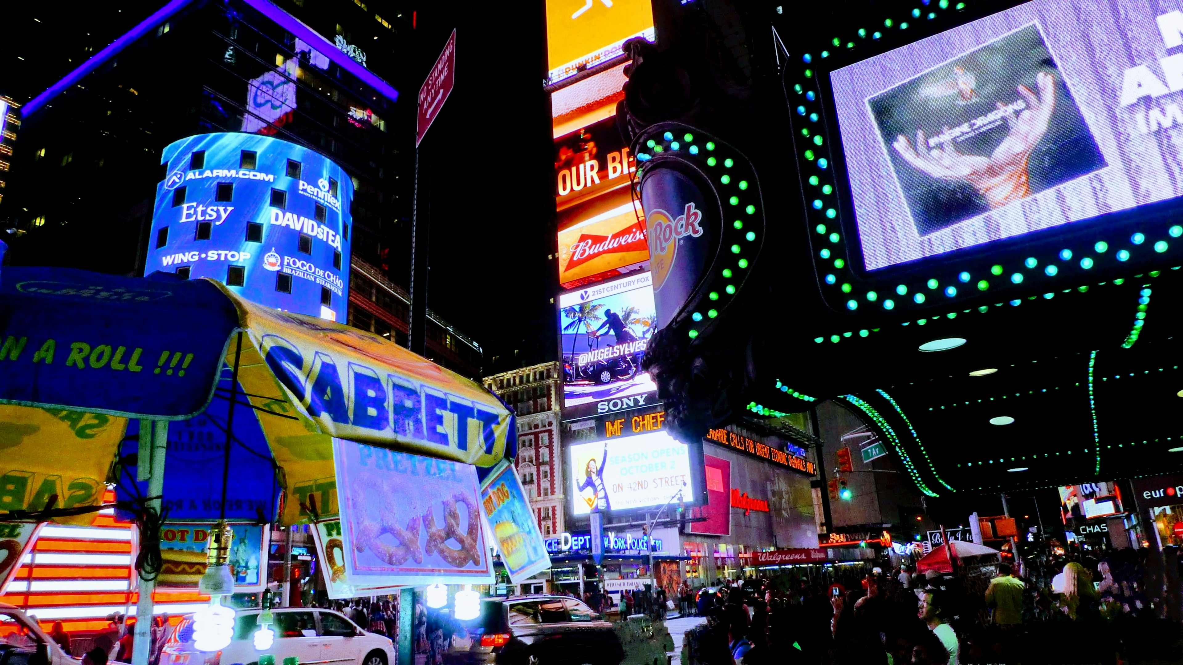 Night view of Times Square featuring a hot dog stand and neon signs