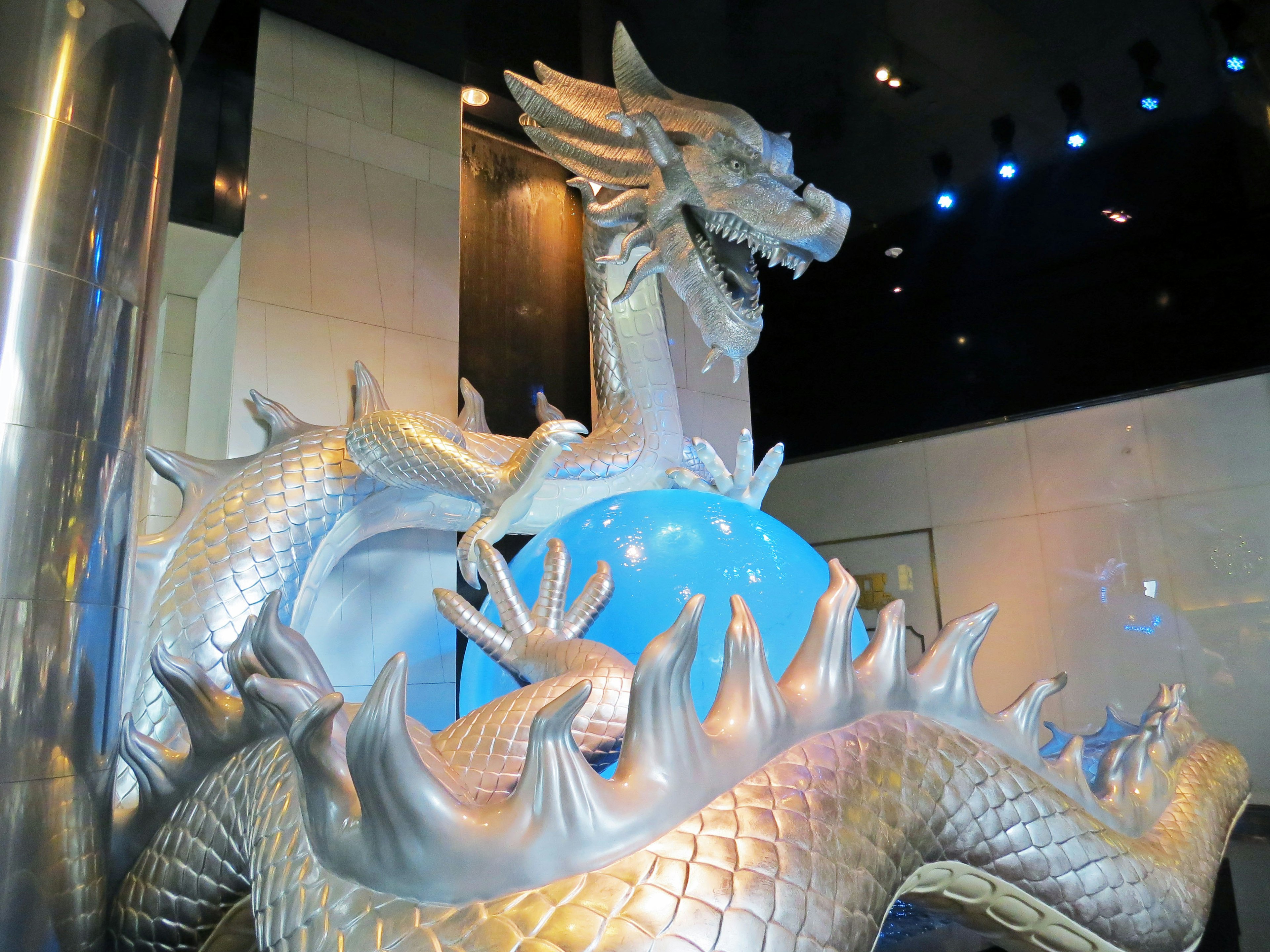 Silver dragon sculpture holding a blue orb