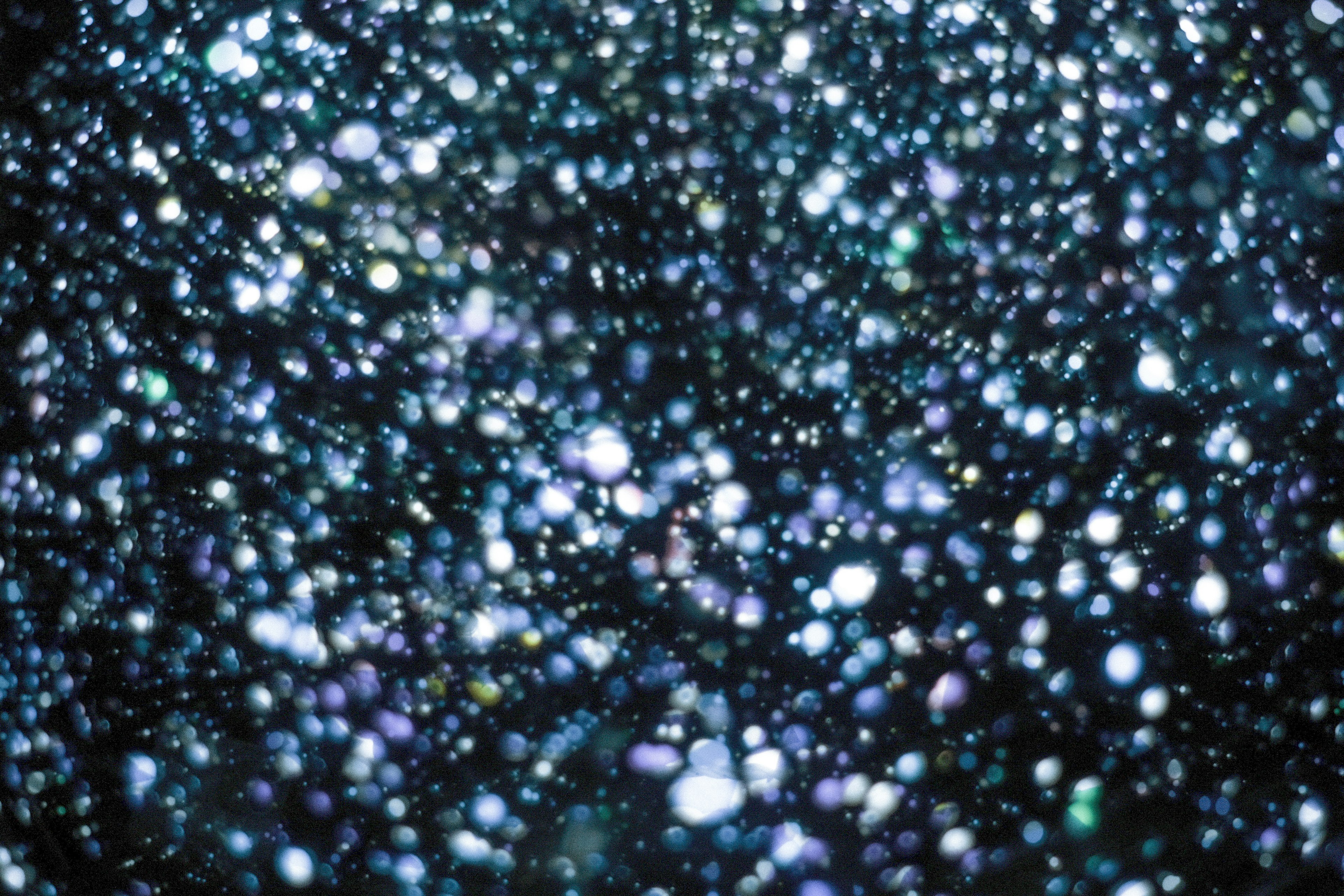 A dark background filled with scattered blue and purple light spots