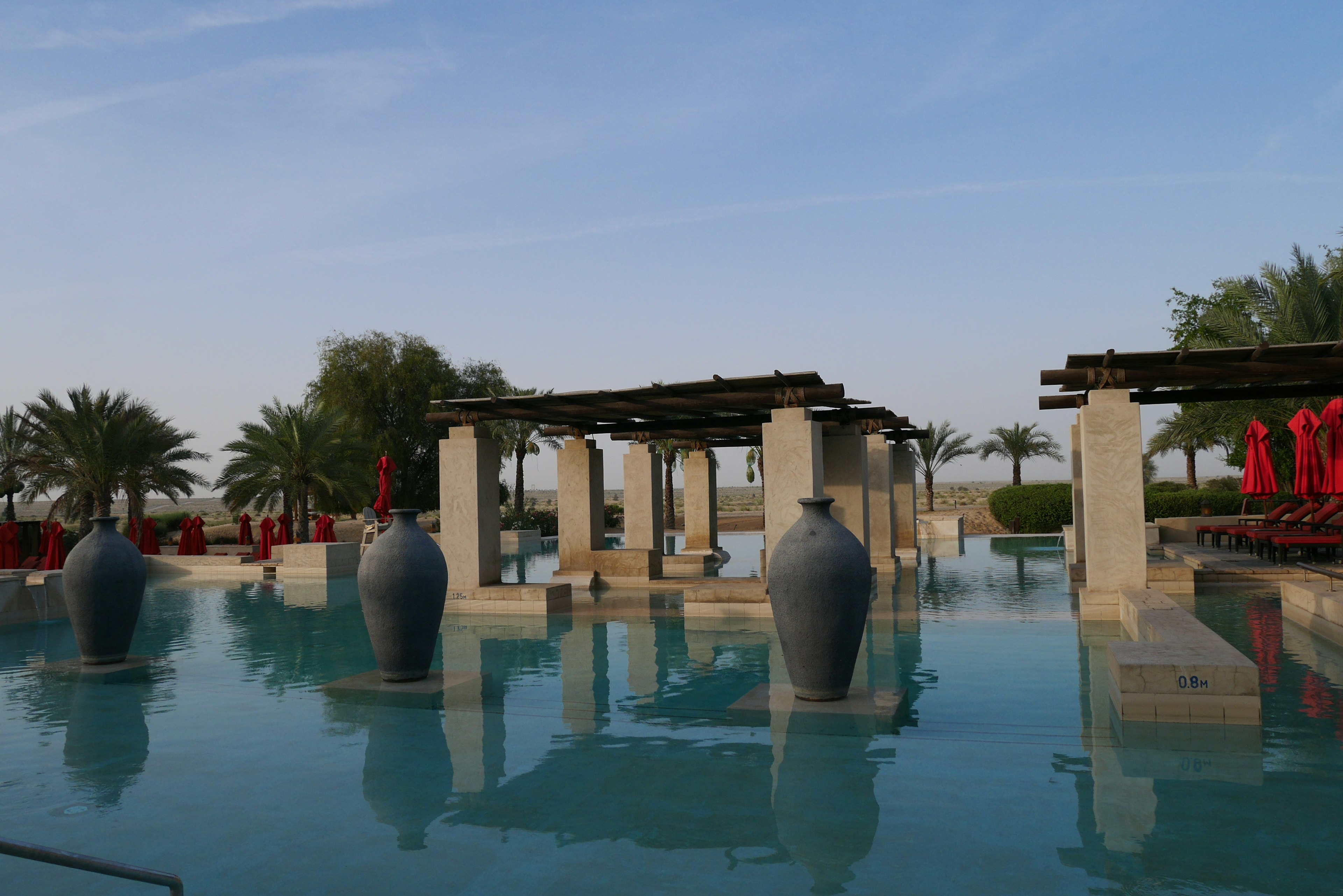 Resort view featuring large vases on a blue water surface with red umbrellas