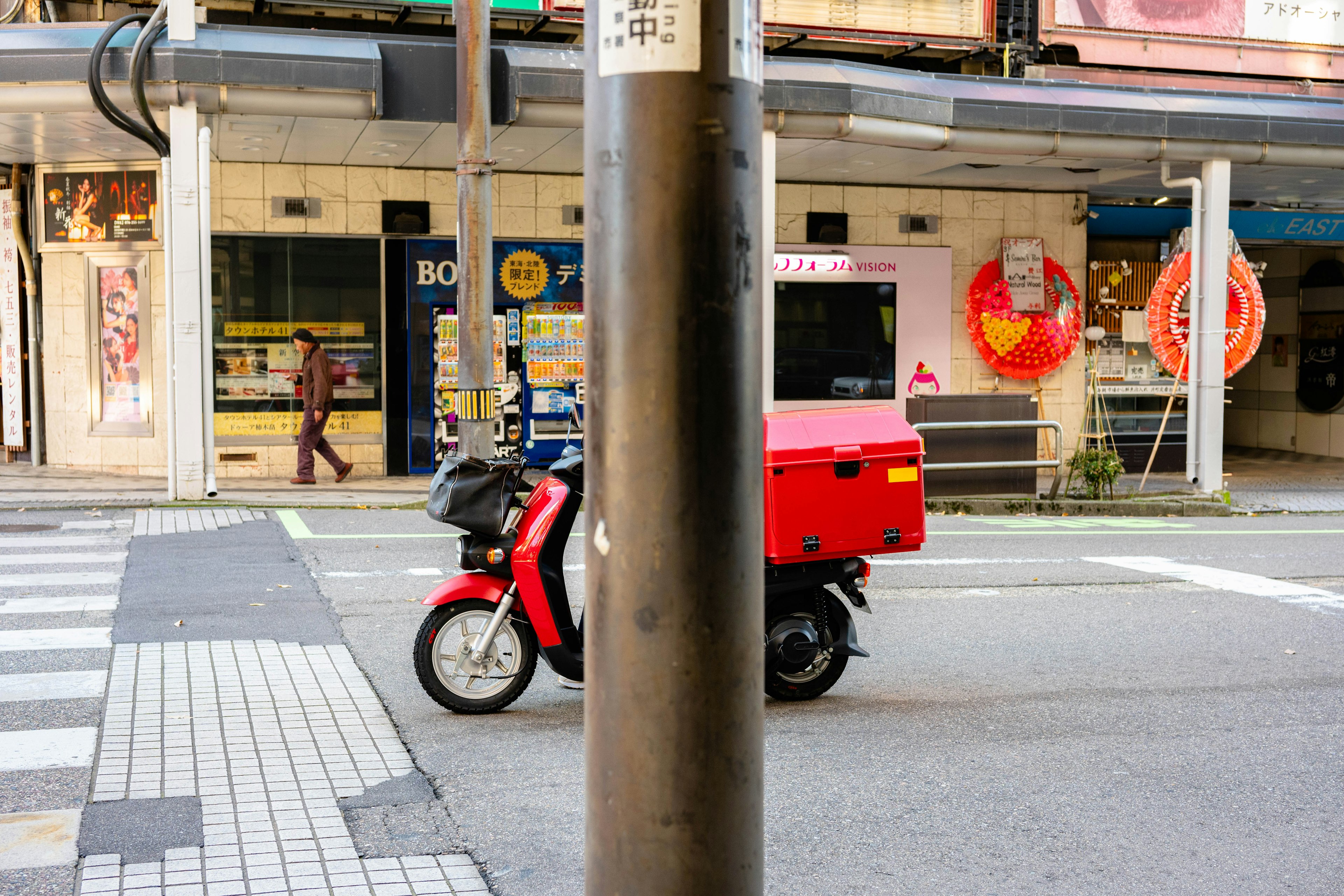 赤い配達バイクが街の交差点を通過している