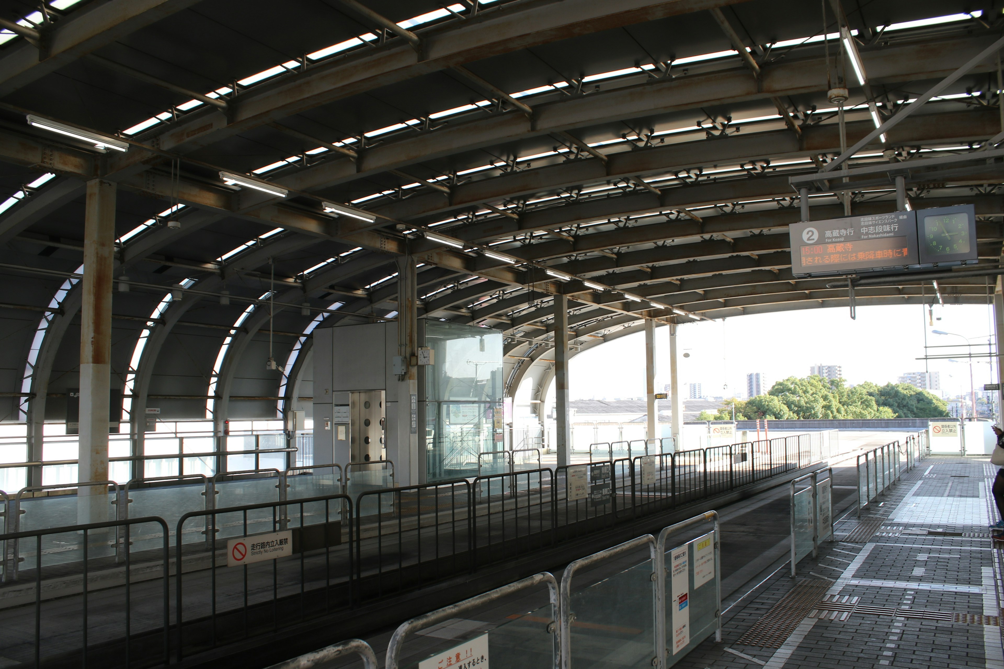 ชานชาลาสถานีรถไฟที่มีหลังคาโค้งและภูมิทัศน์โดยรอบ