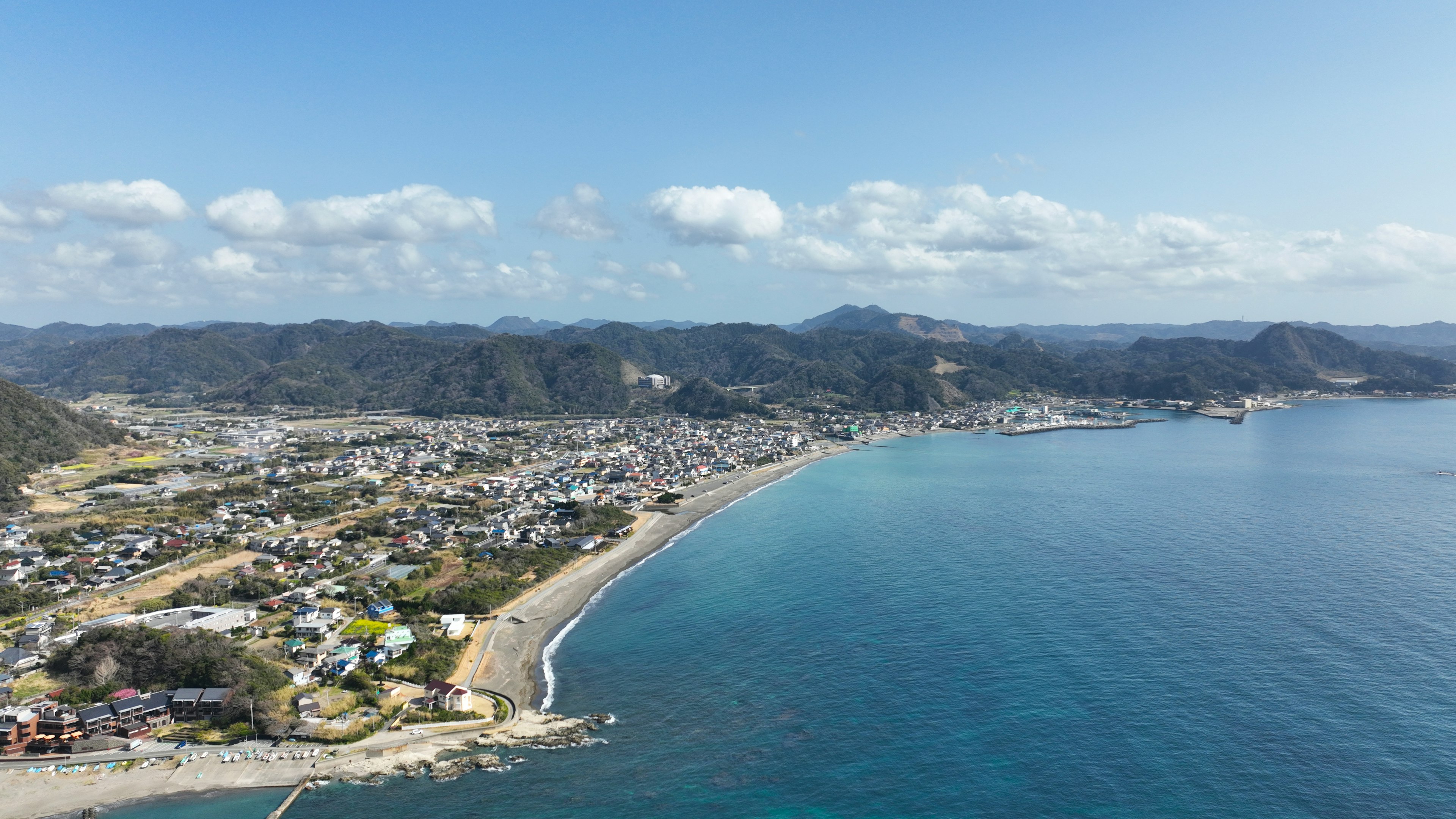 Aerial view of a coastal town with a curved beach and clear blue water