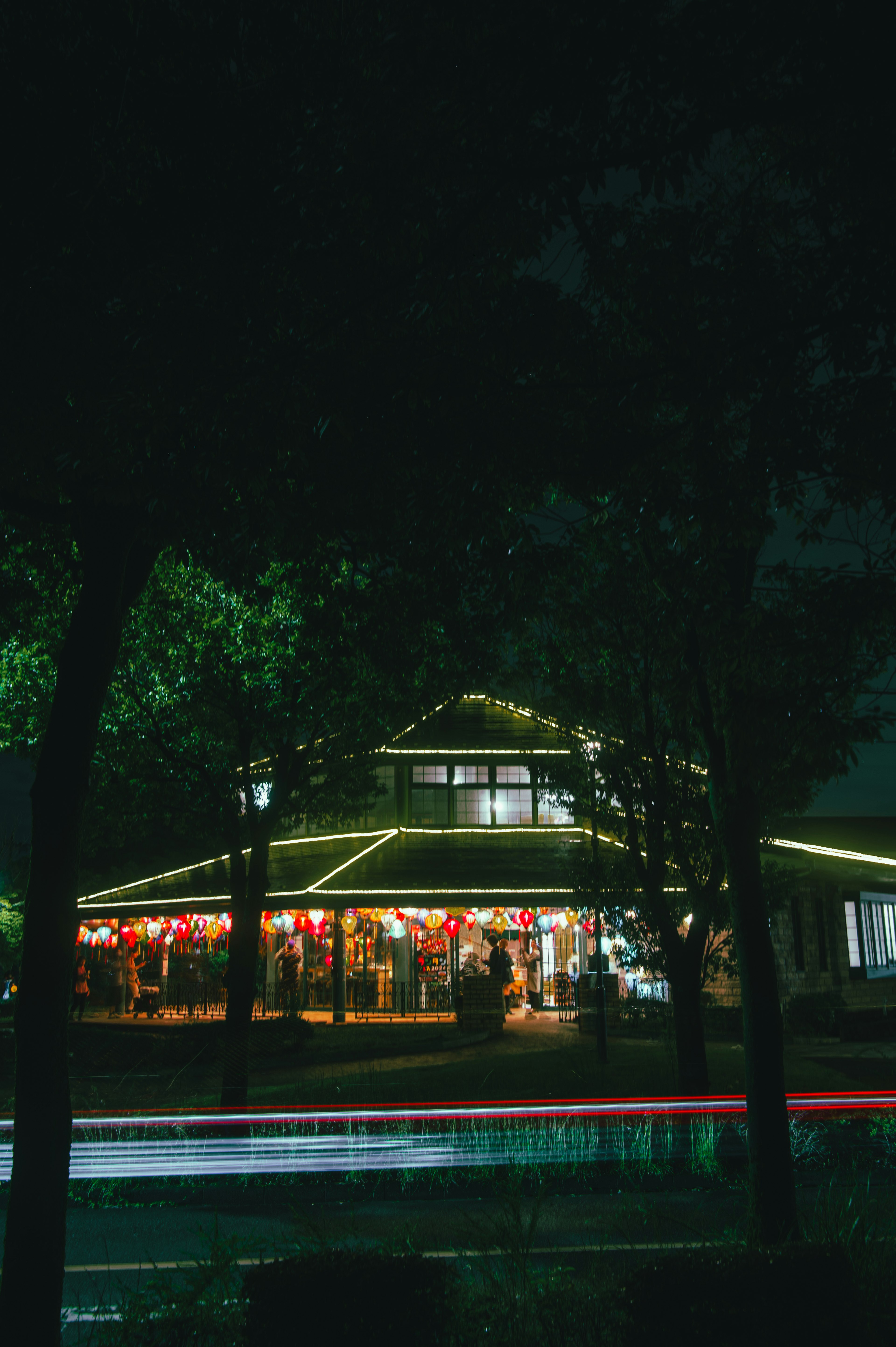 Edificio circular iluminado por la noche rodeado de árboles