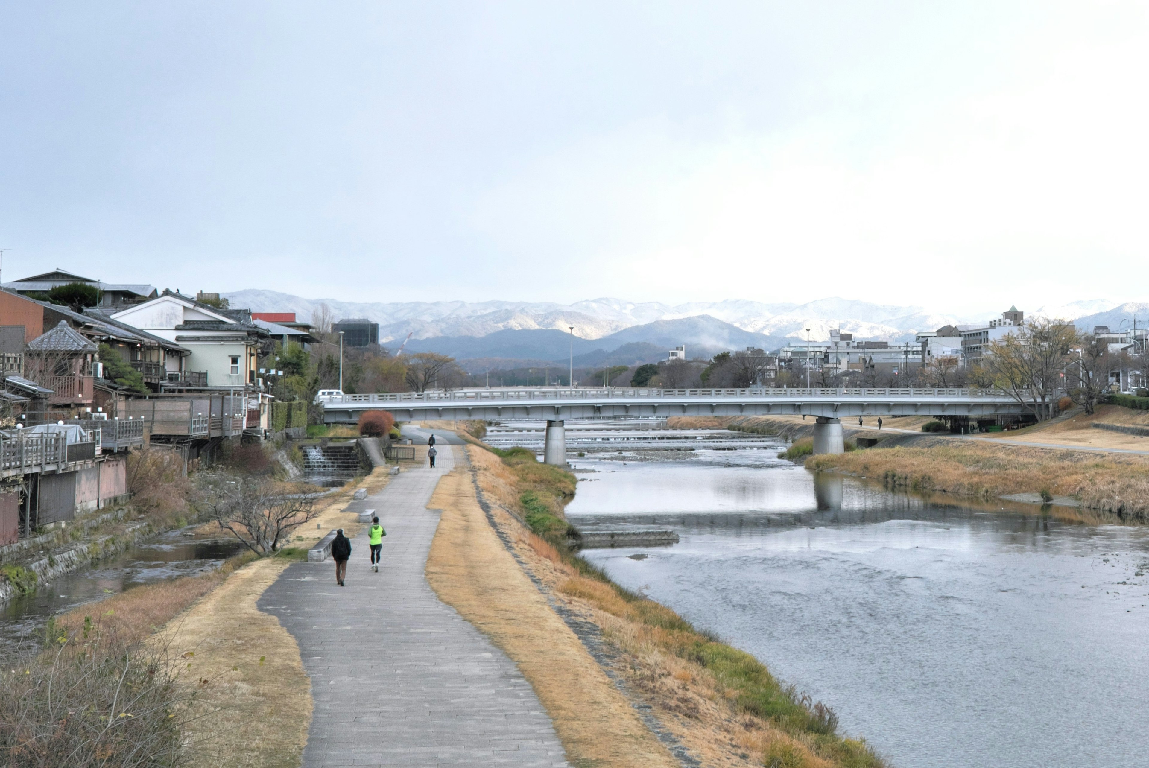 静かな川沿いの散歩道と山々の背景