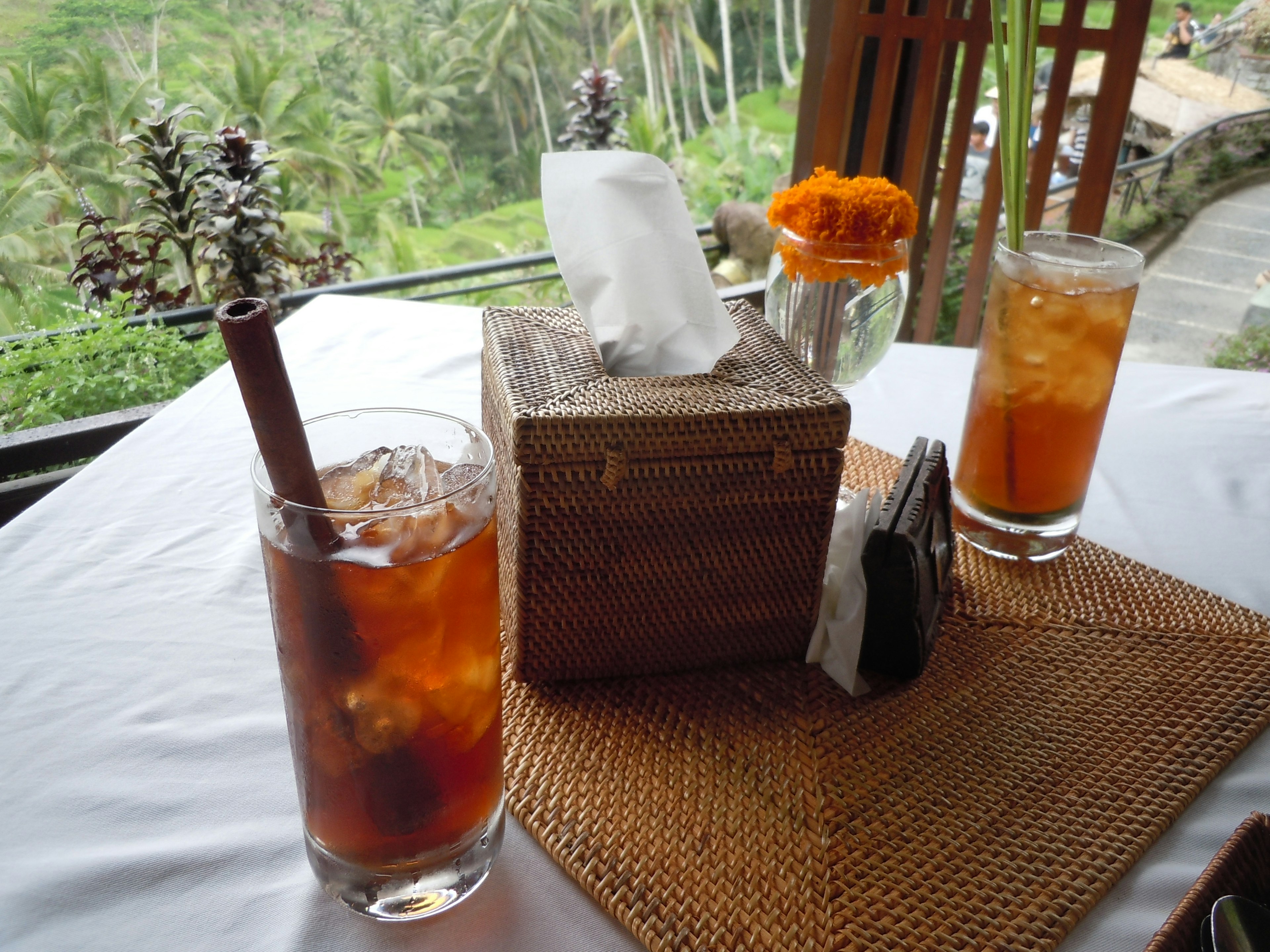 Tischdekoration mit Eistee und orangefarbenen Blumen in einem natürlichen Restaurant