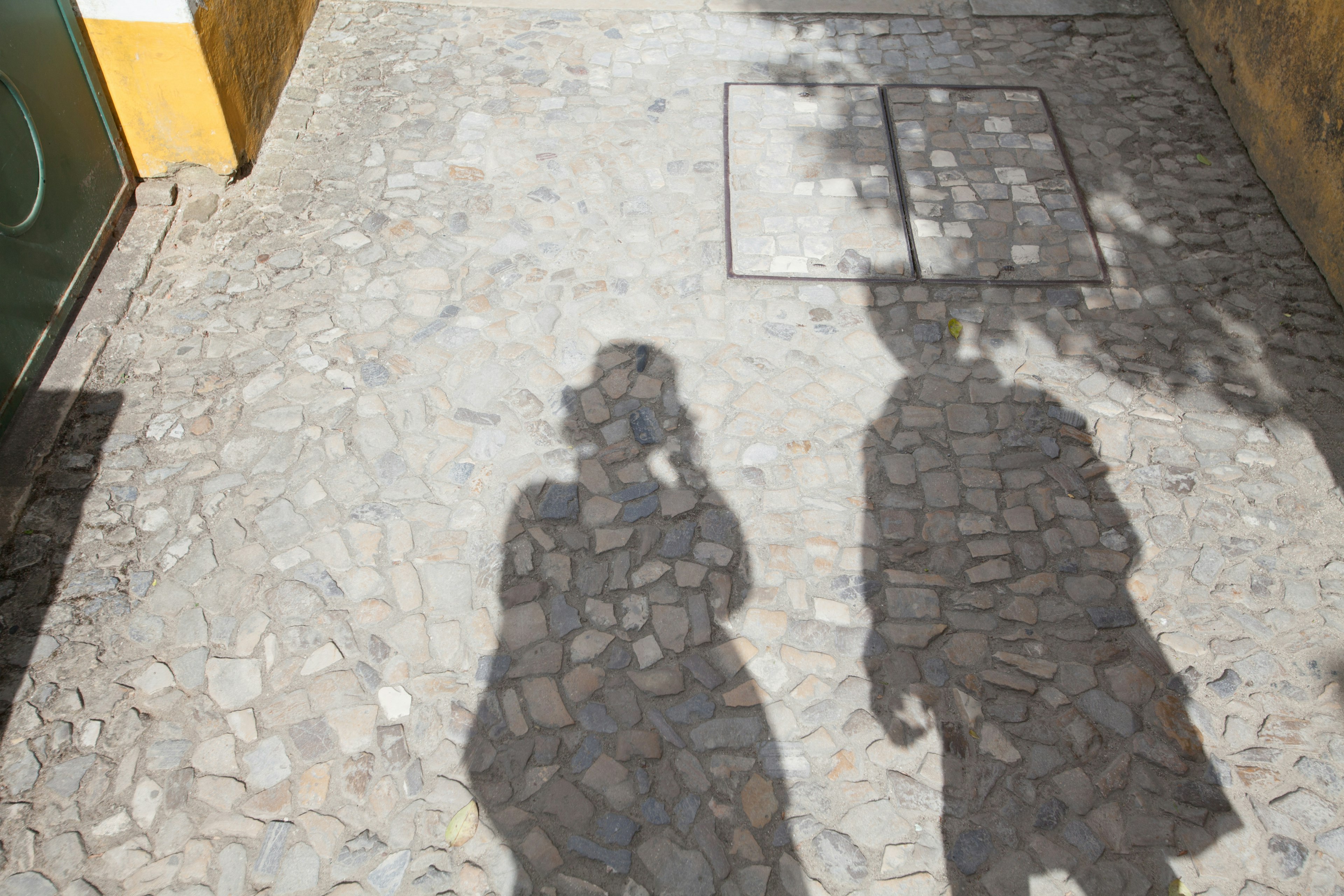 Silhouettes of two people walking on a cobblestone path