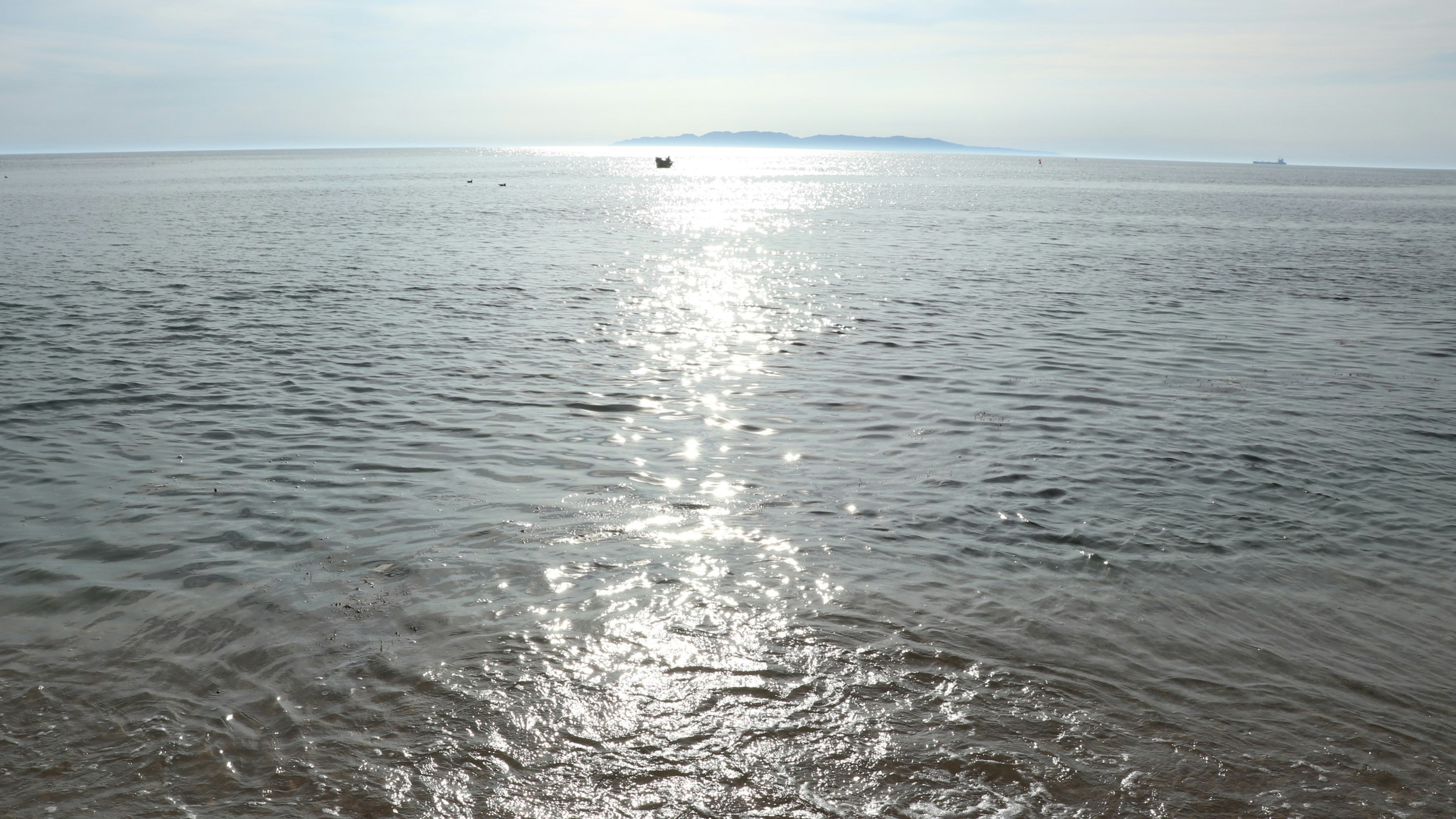 Mare calmo che riflette la luce del sole con onde scintillanti