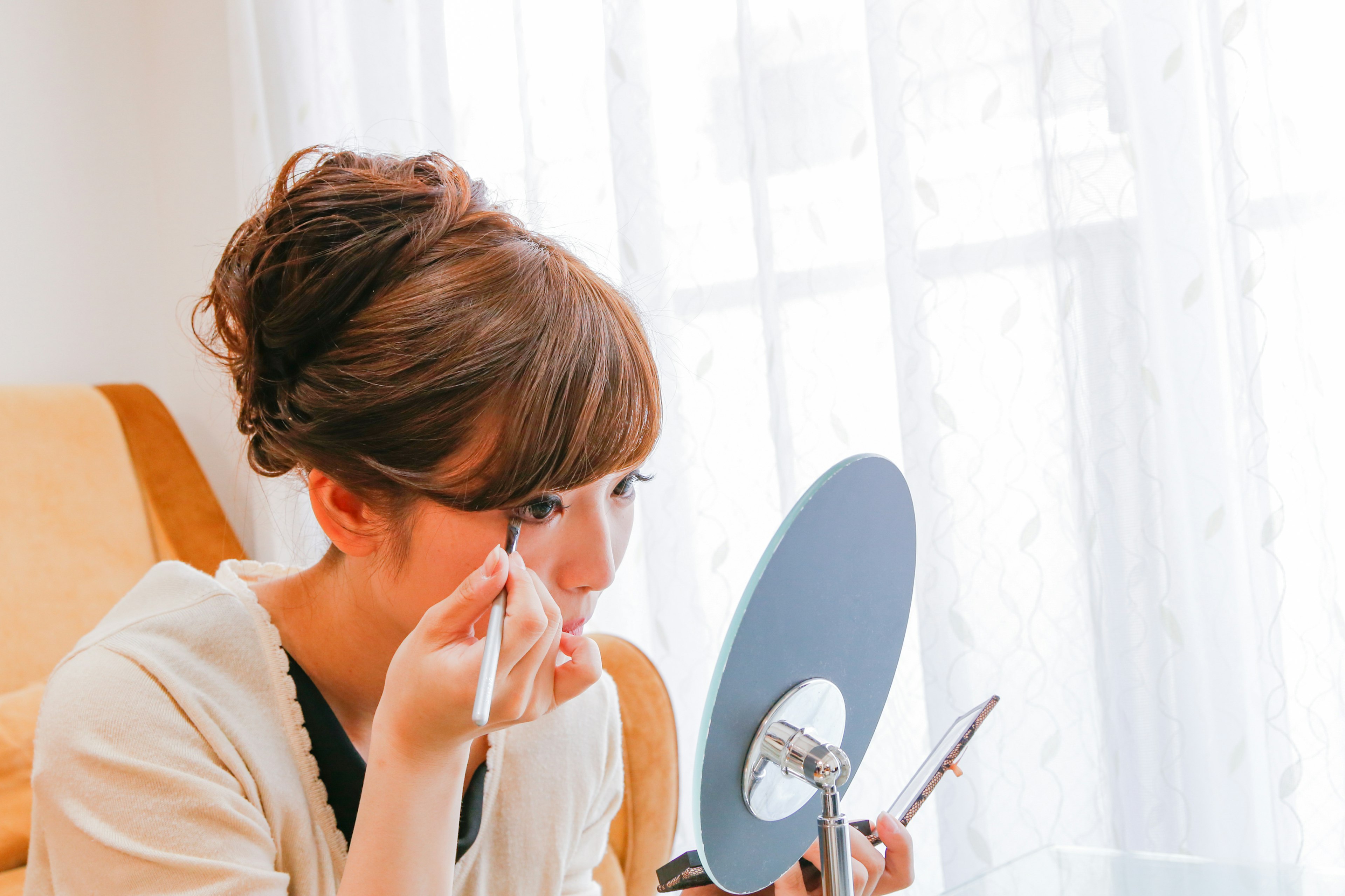 Mujer aplicándose maquillaje mientras mira en un espejo