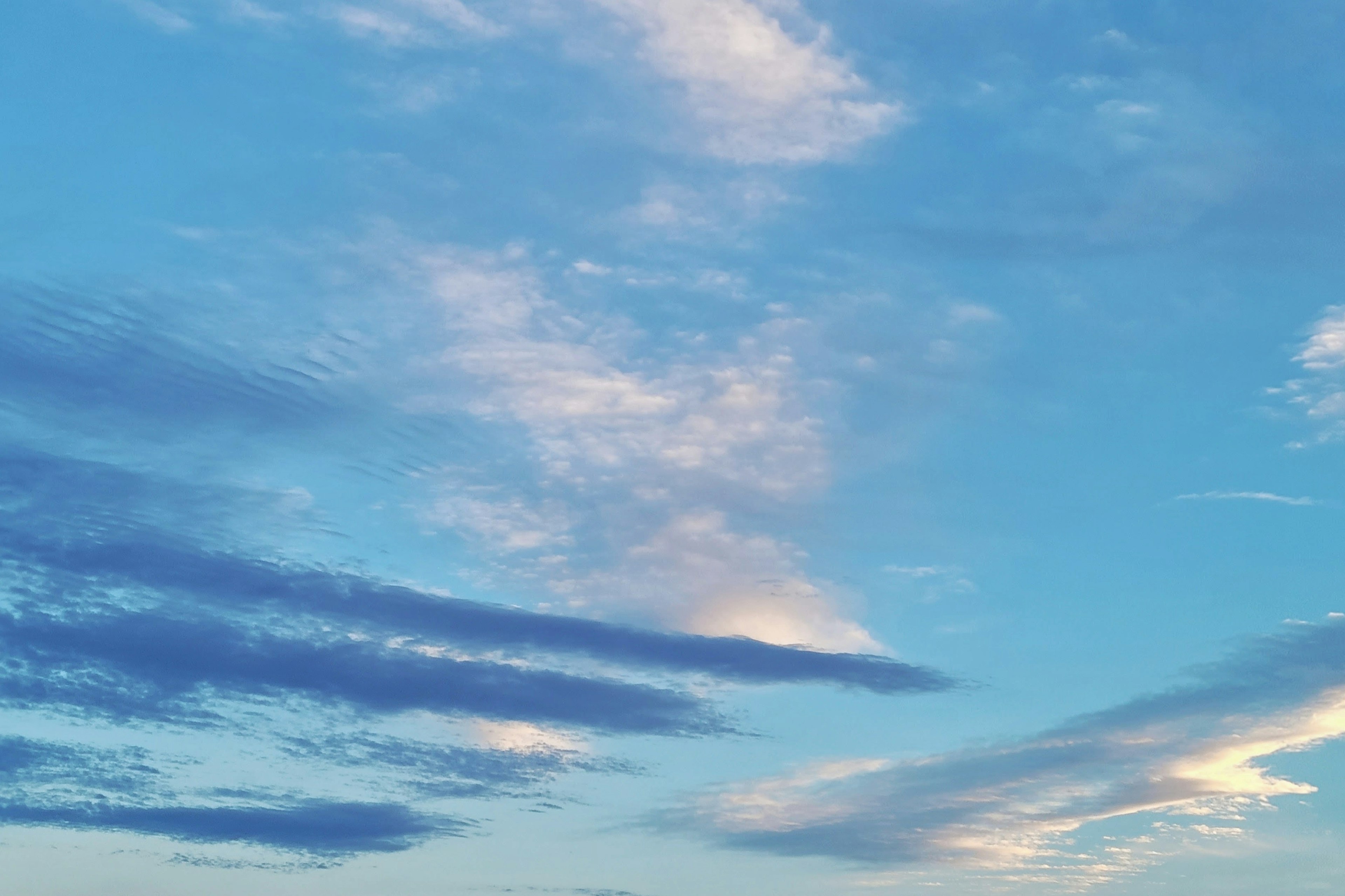 Eine Landschaft mit blauem Himmel, weißen Wolken und zarten lila Wolkensträngen