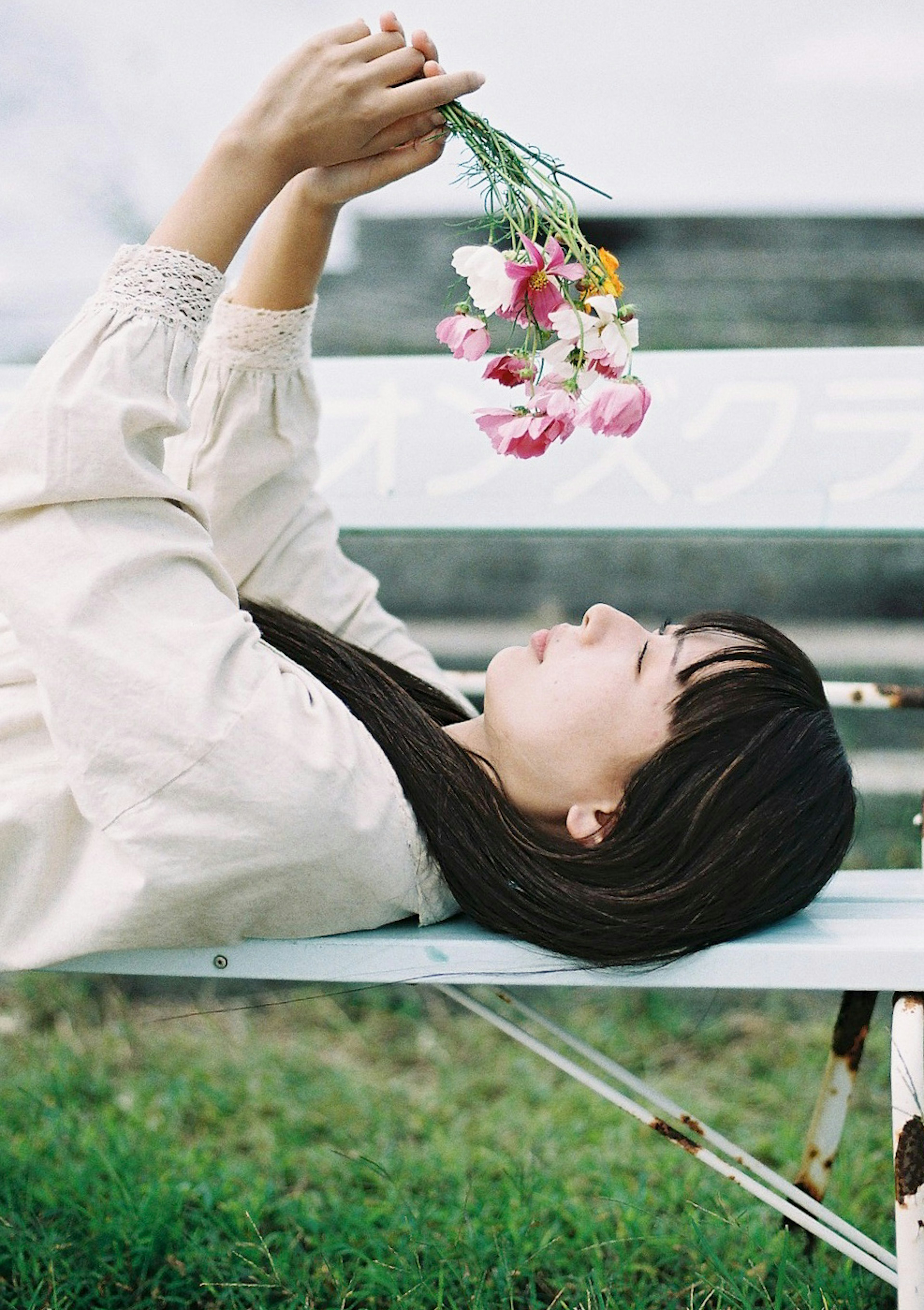 A woman lying on a bench holding a bouquet of flowers