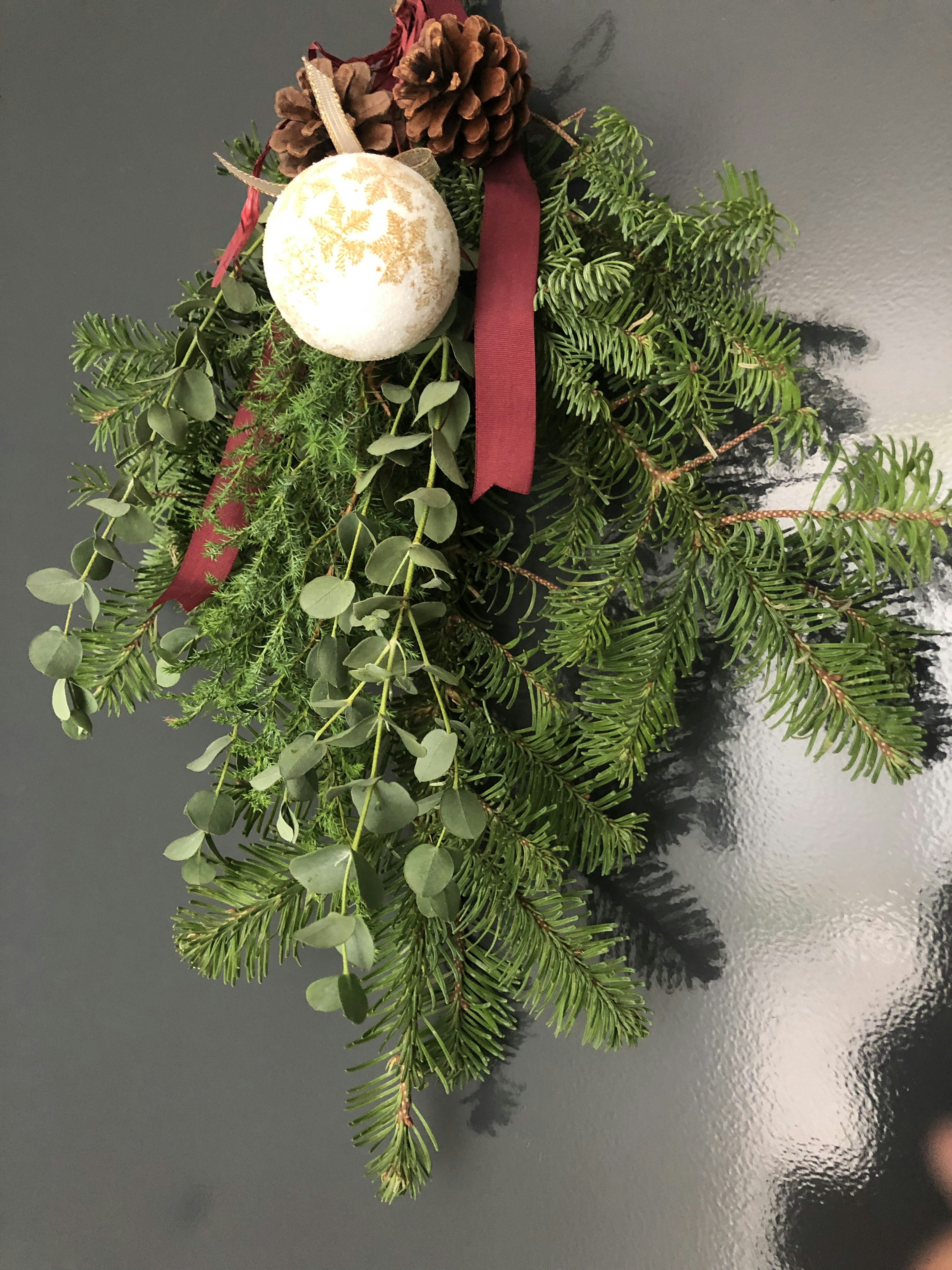 Décoration de Noël avec feuillage vert cônes de pin ruban rouge et ornement blanc