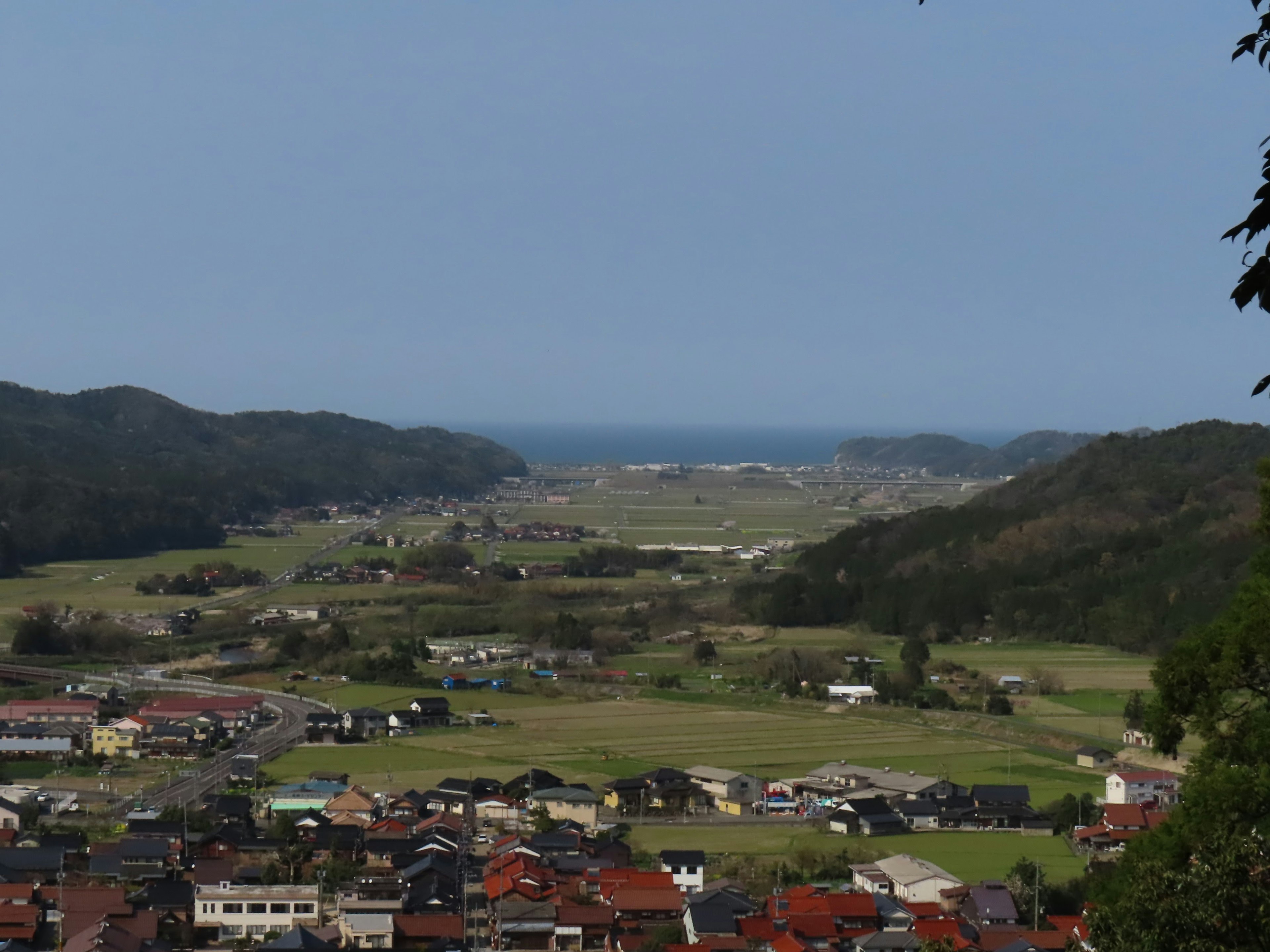 Paysage de village pittoresque entouré de collines vertes et d'un océan bleu