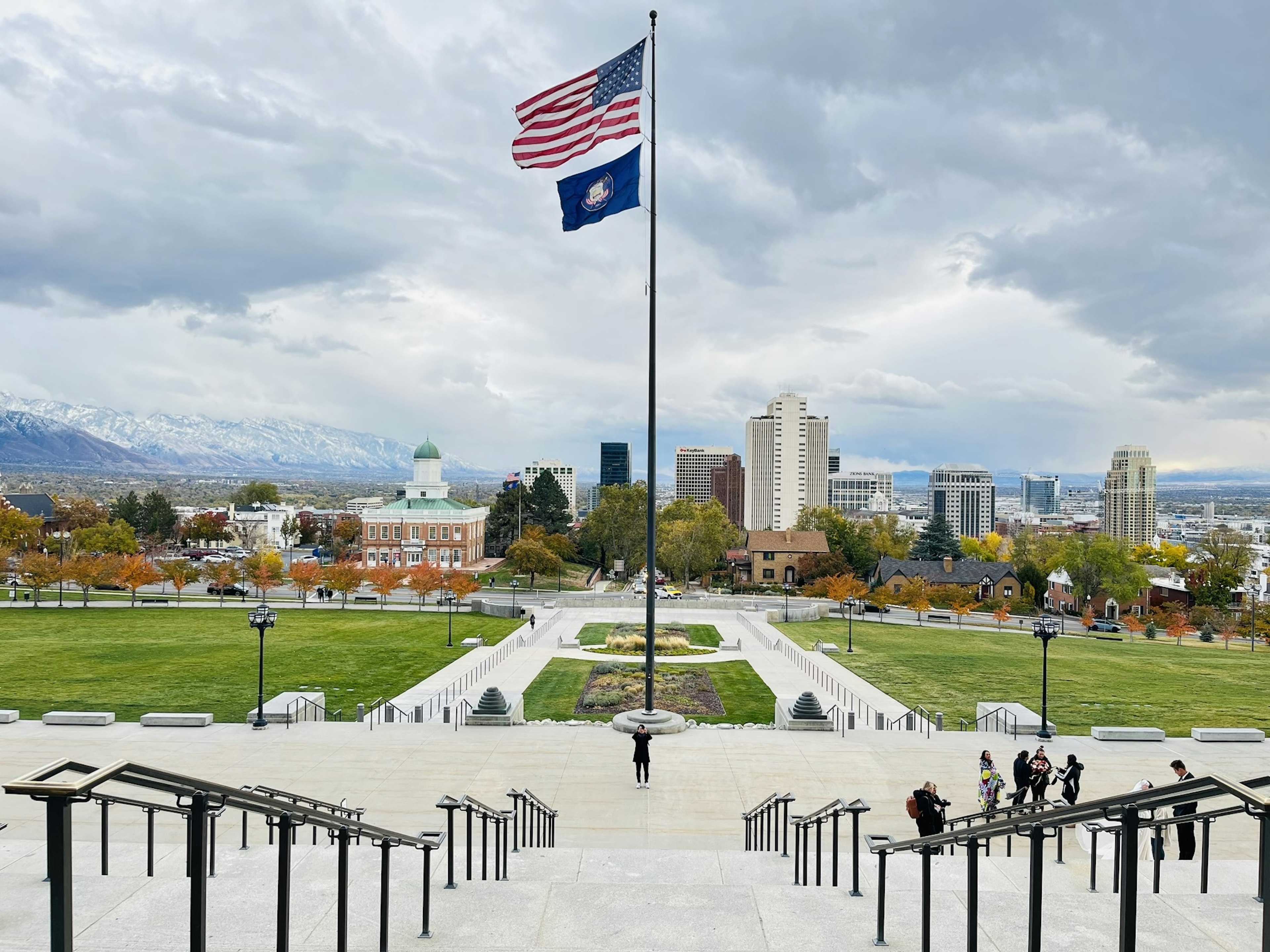 Pemandangan plaza yang menampilkan bendera Amerika dan bendera Utah dengan latar belakang cakrawala kota