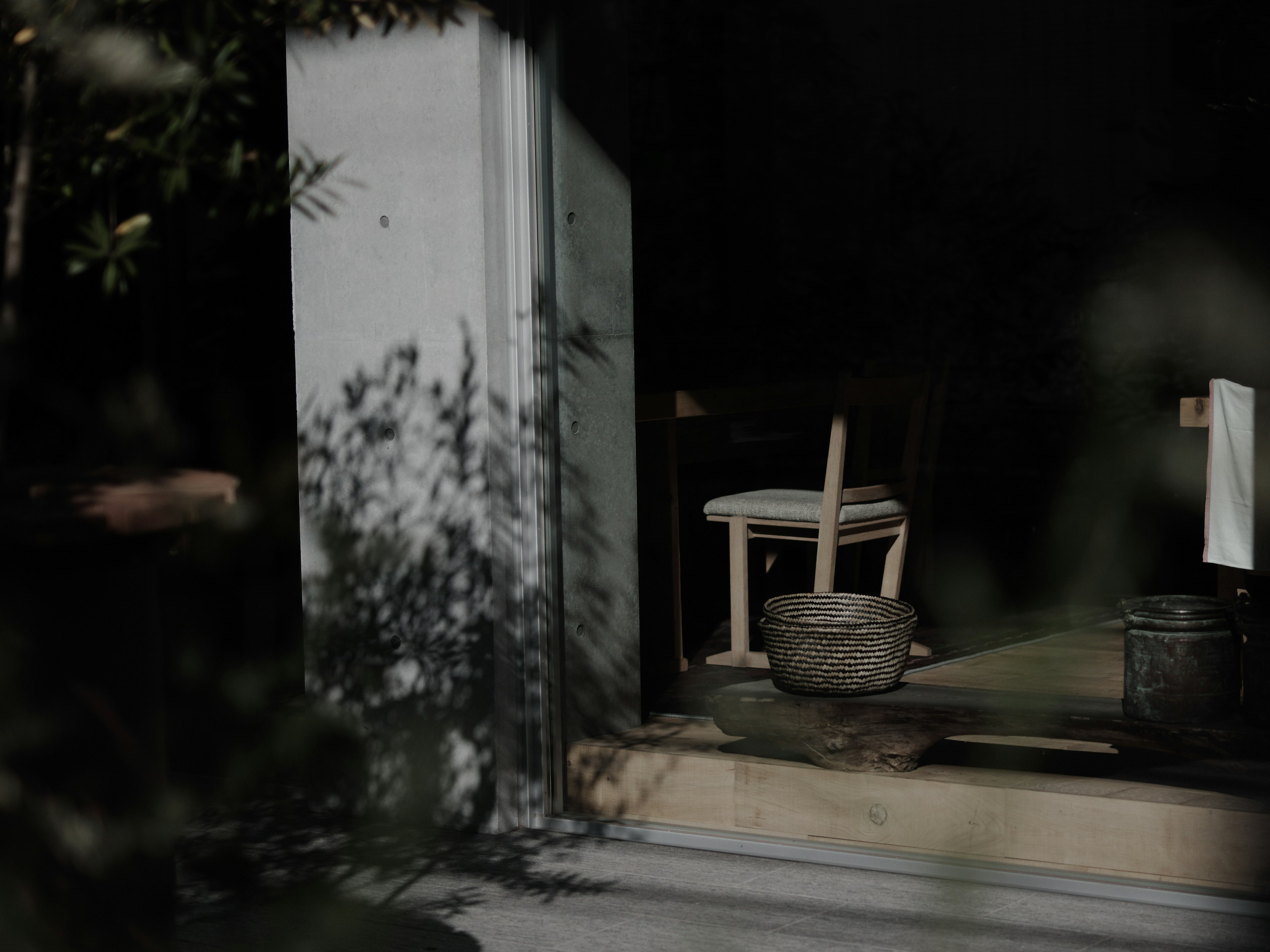 Espacio interior simple con una silla de madera y un cuenco de piedra en un fondo oscuro