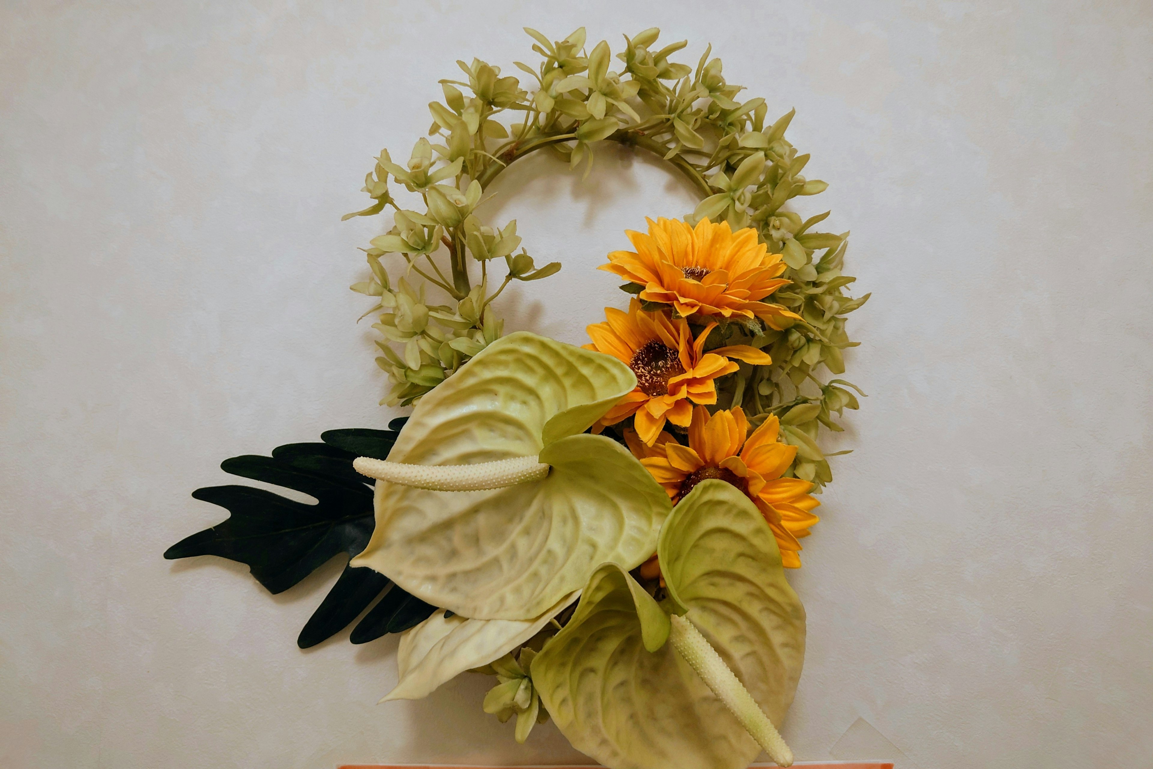 緑と黄色の花で飾られたリースの画像