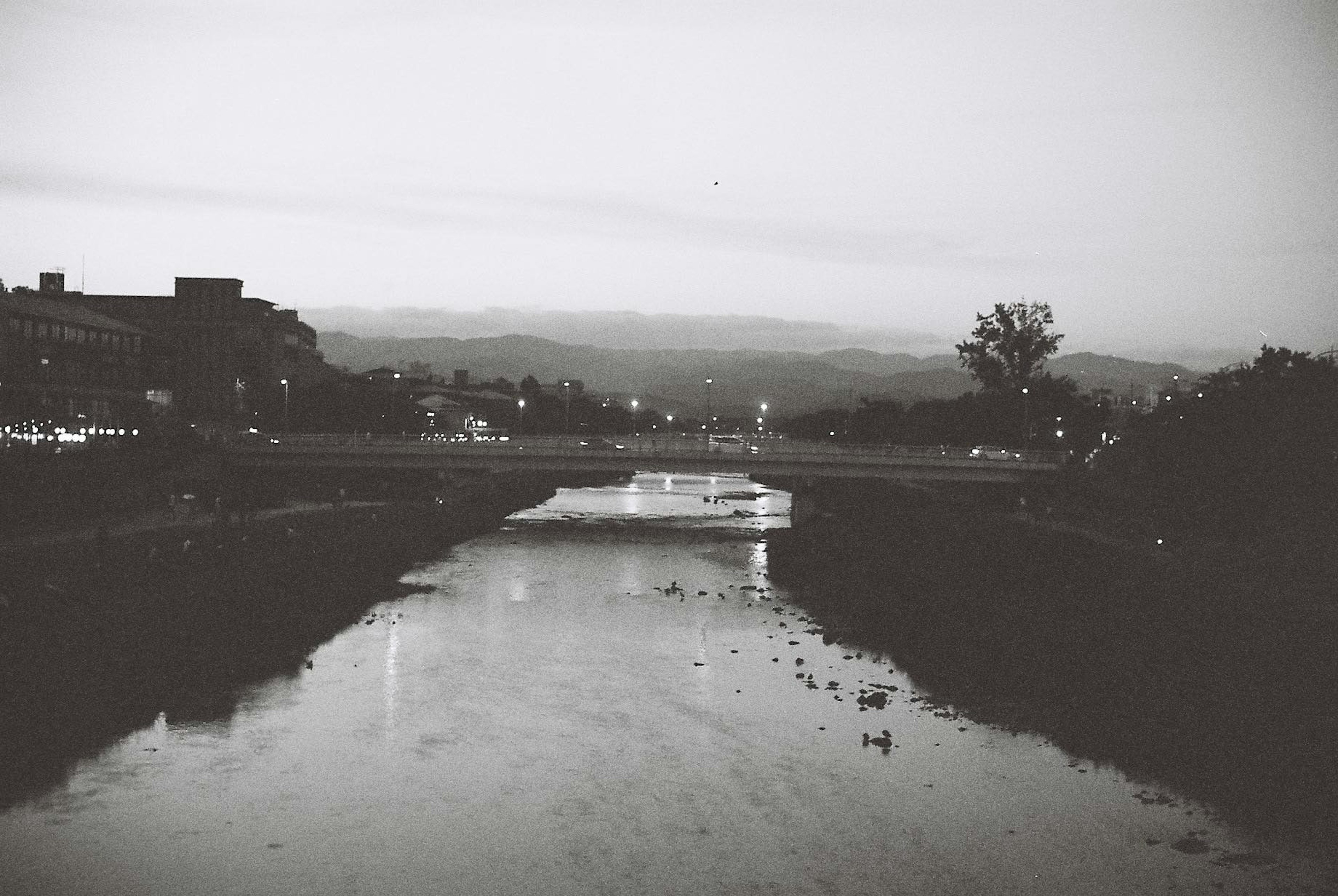 Escena de río al atardecer con montañas a lo lejos