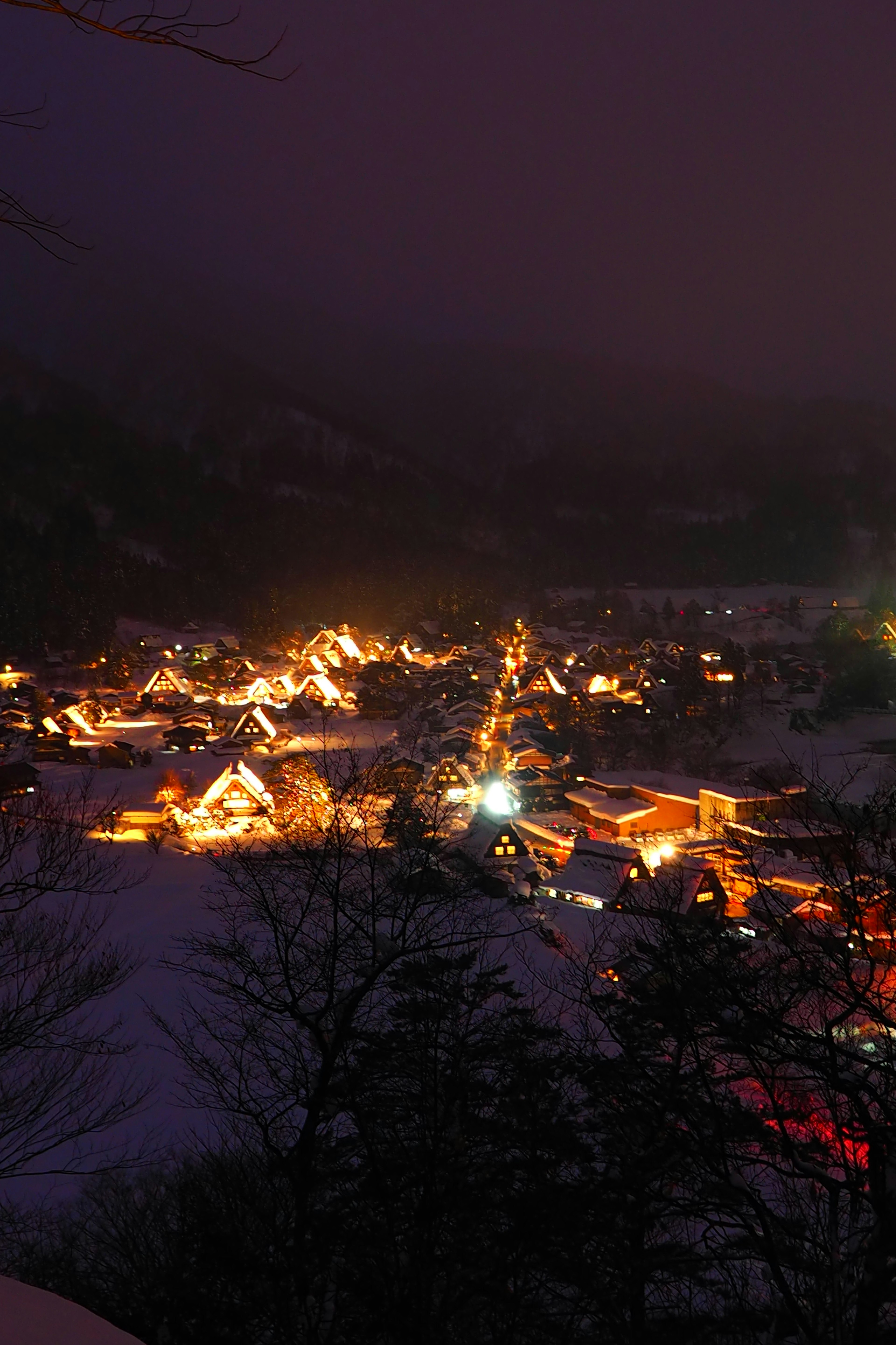 Snow-covered village at night with glowing traditional buildings