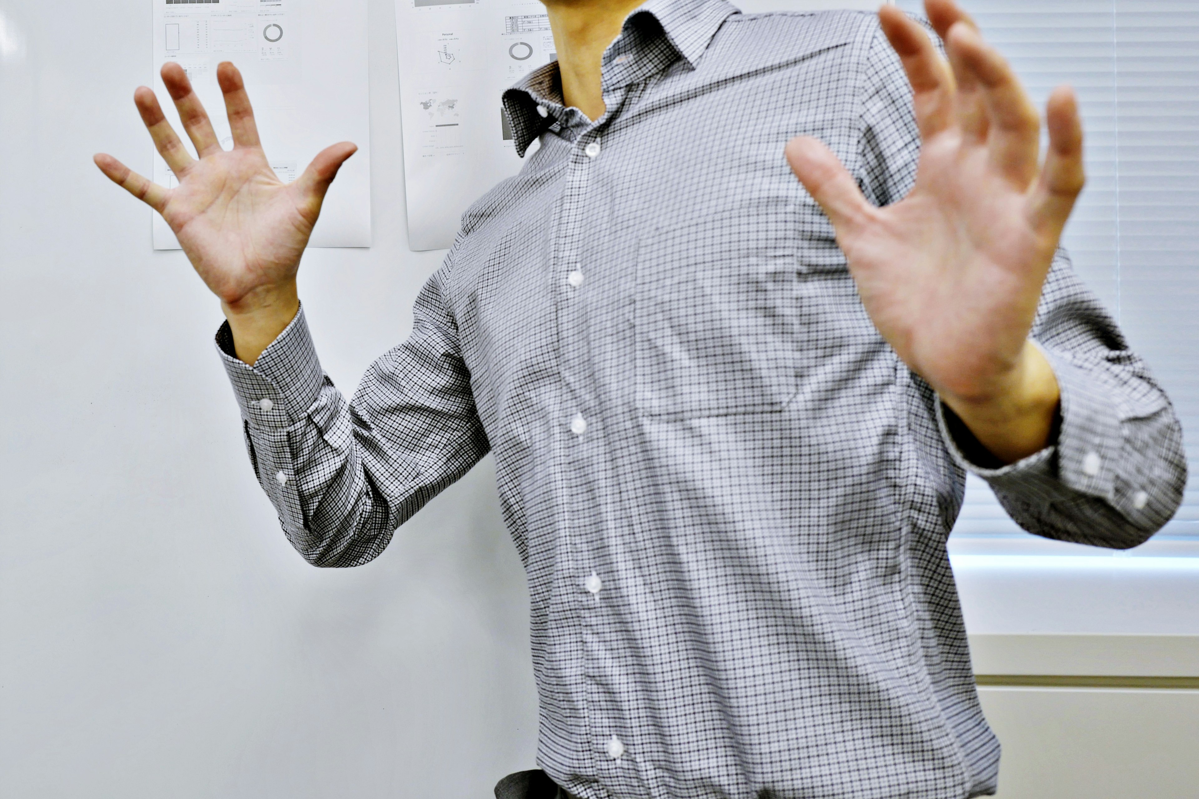 Man with spread hands wearing a checkered shirt