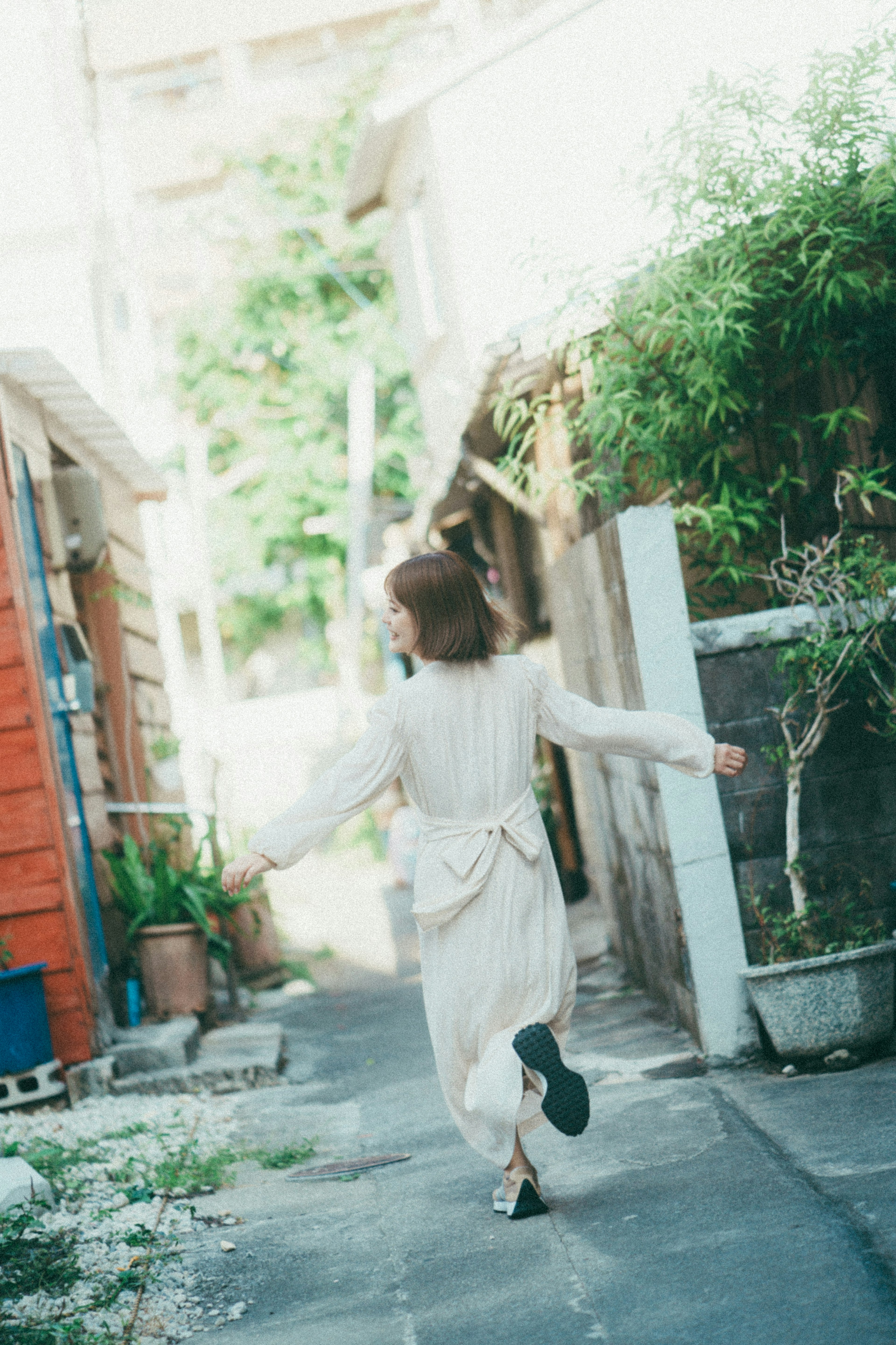 Une femme en robe blanche courant dans une ruelle étroite