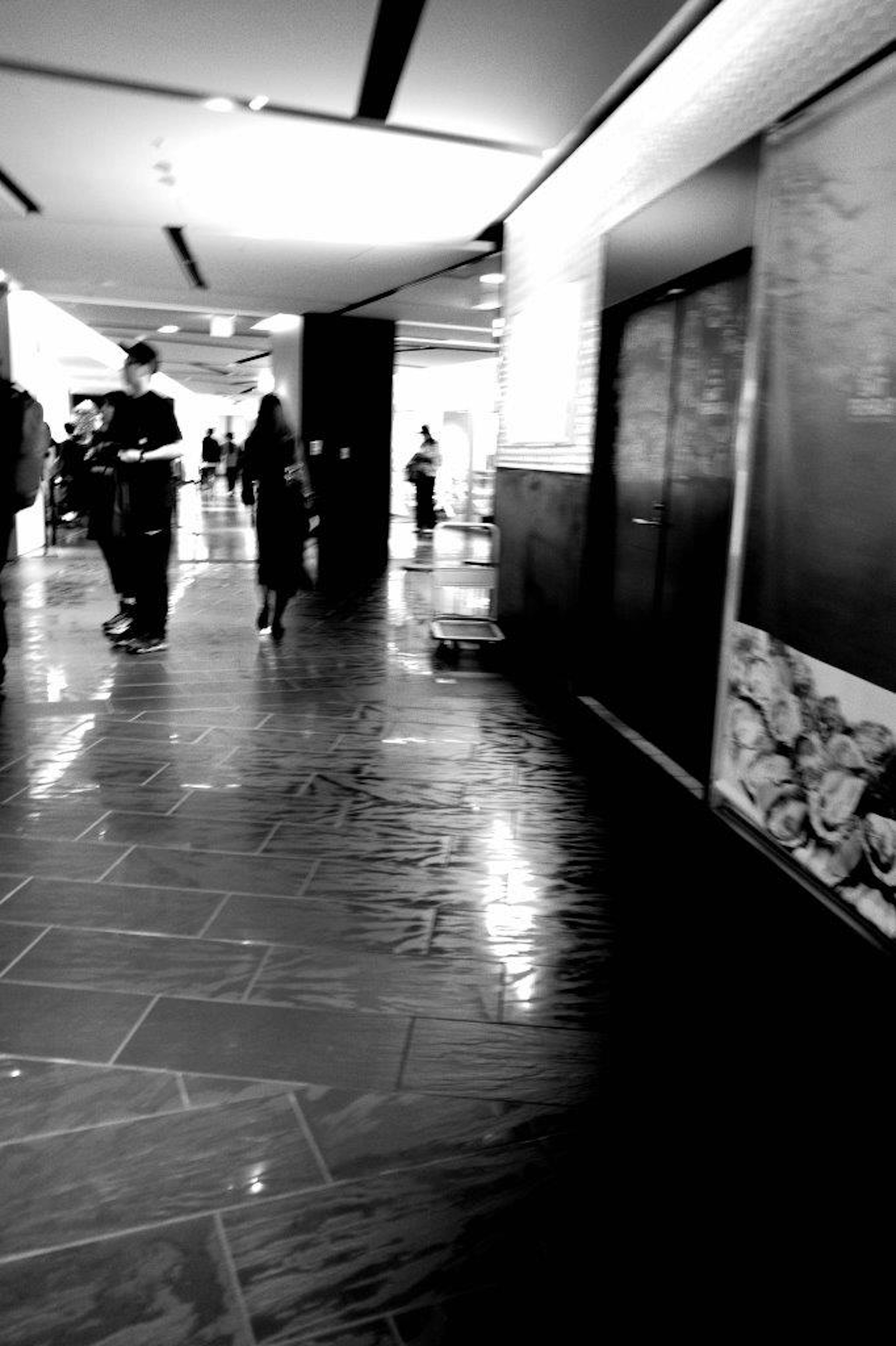 A black and white corridor with people walking