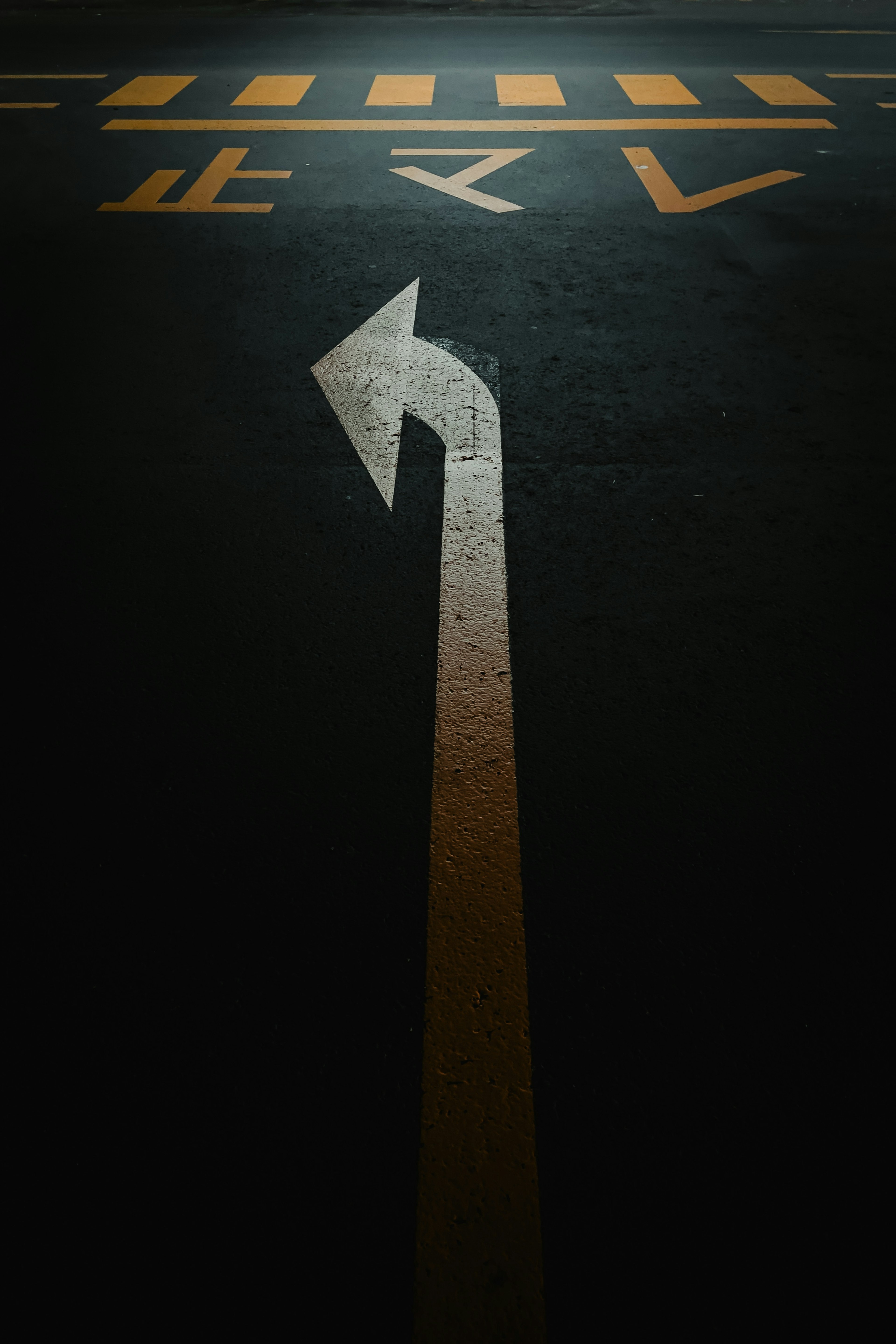 Dark pavement with a left turn arrow and yellow stripes