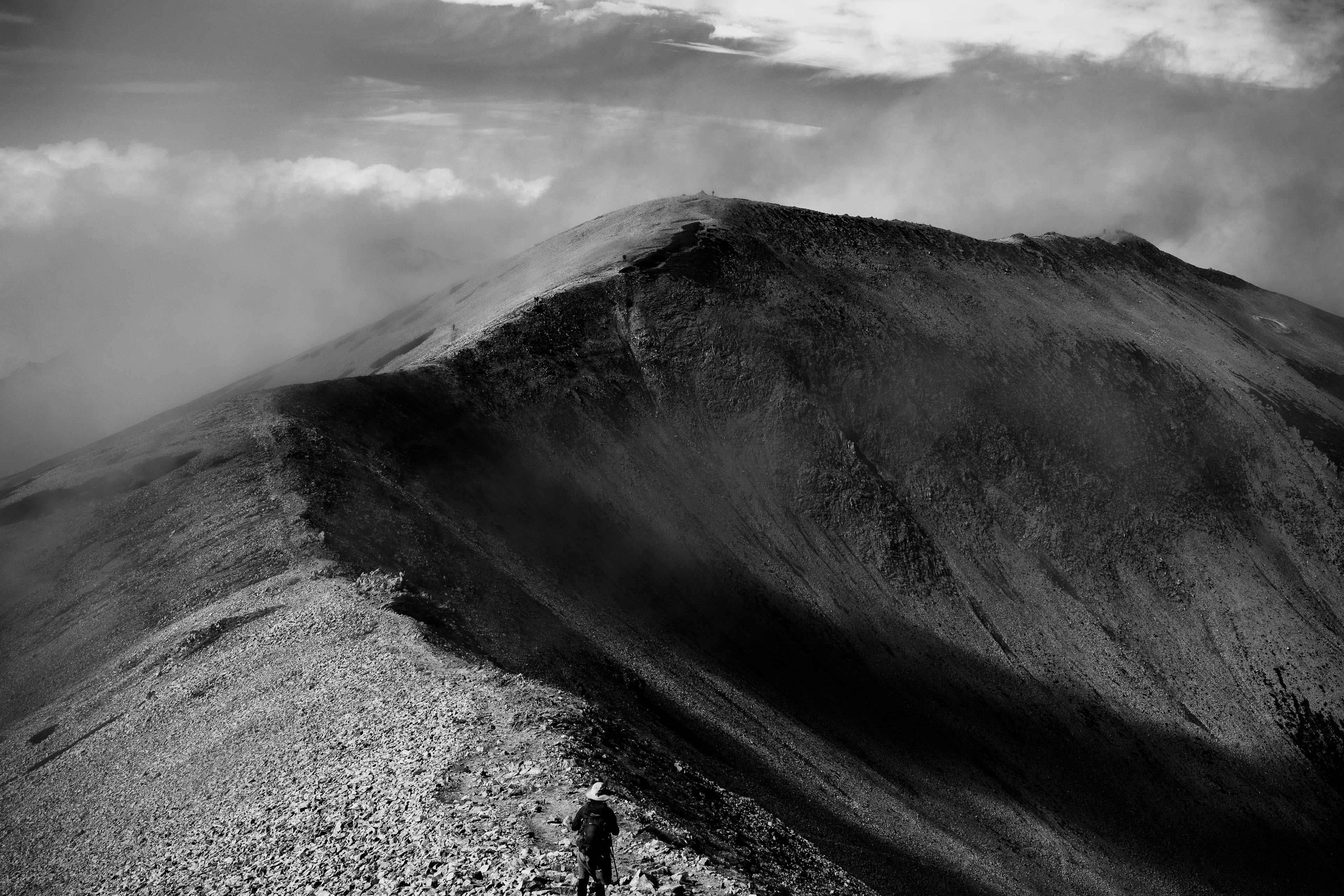 黒白の山の風景に登るハイカーのシルエット