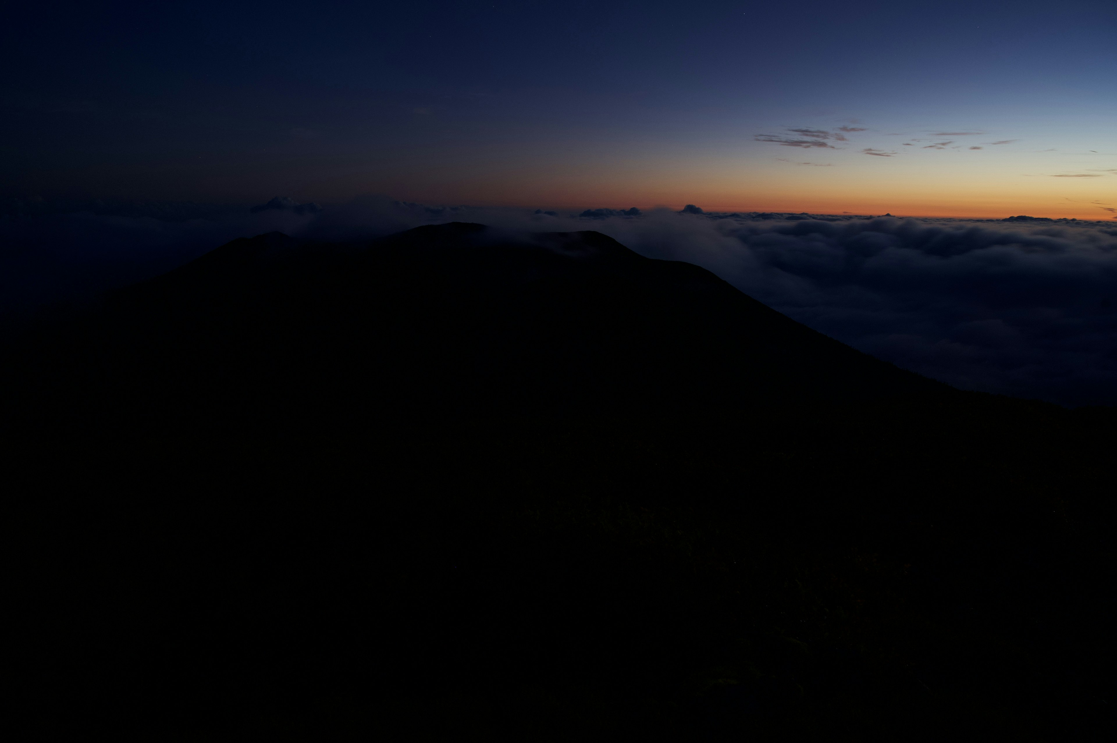 Silhouette d'une montagne sombre contre un horizon de l'aube