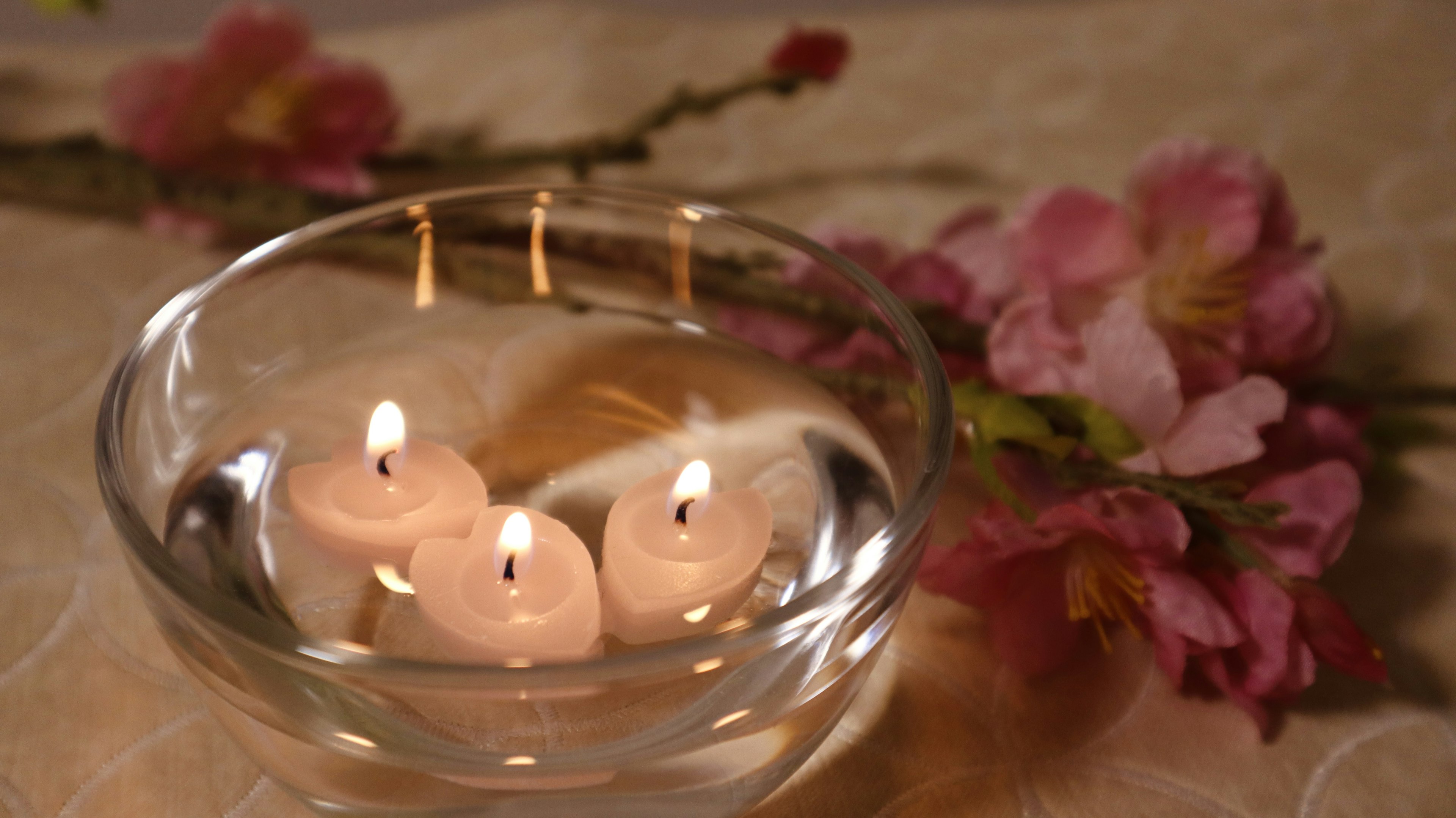 Floating candles in water with pink cherry blossom arrangement