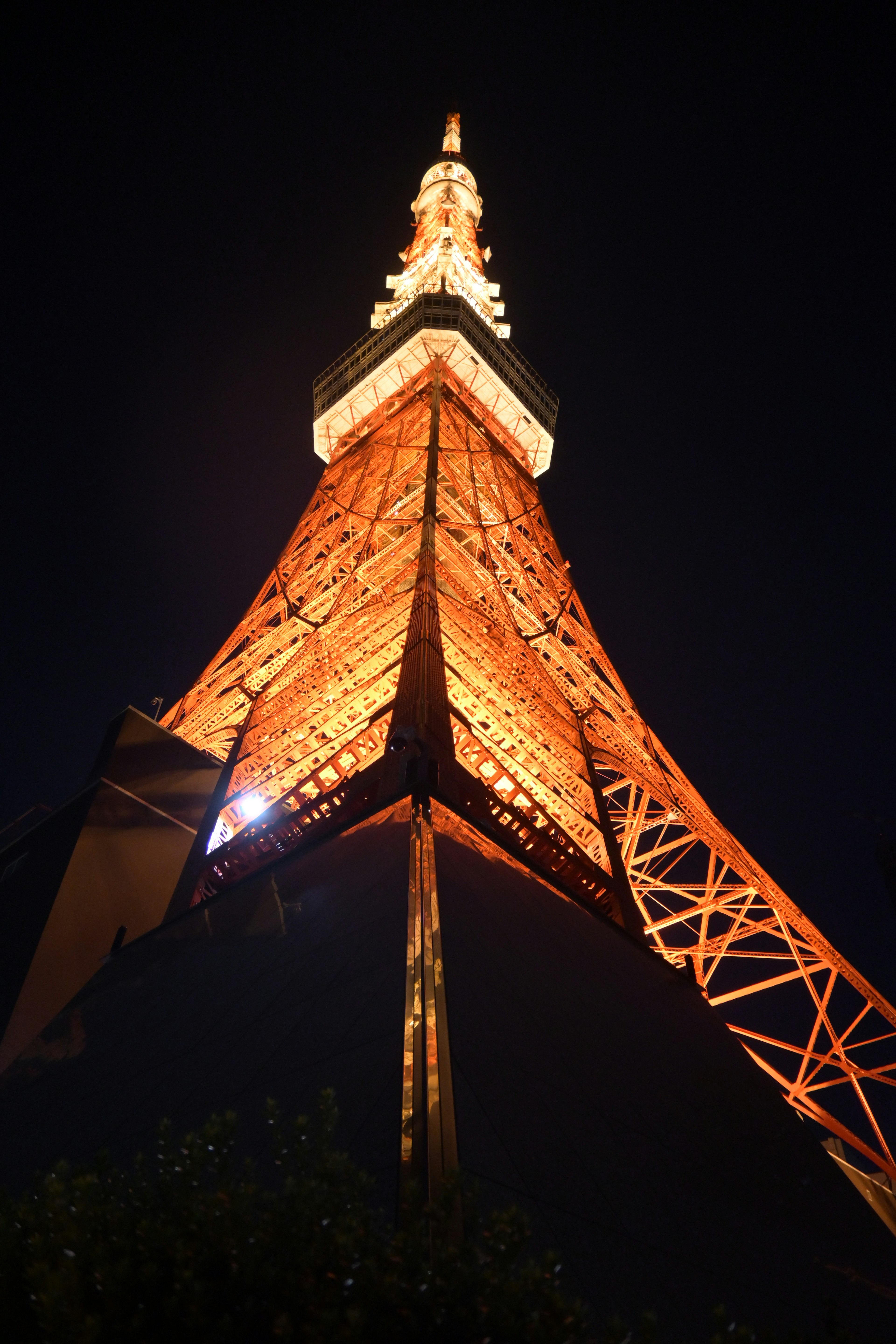 Foto vom Tokyo Tower bei Nacht von unten gesehen orange leuchtende Struktur