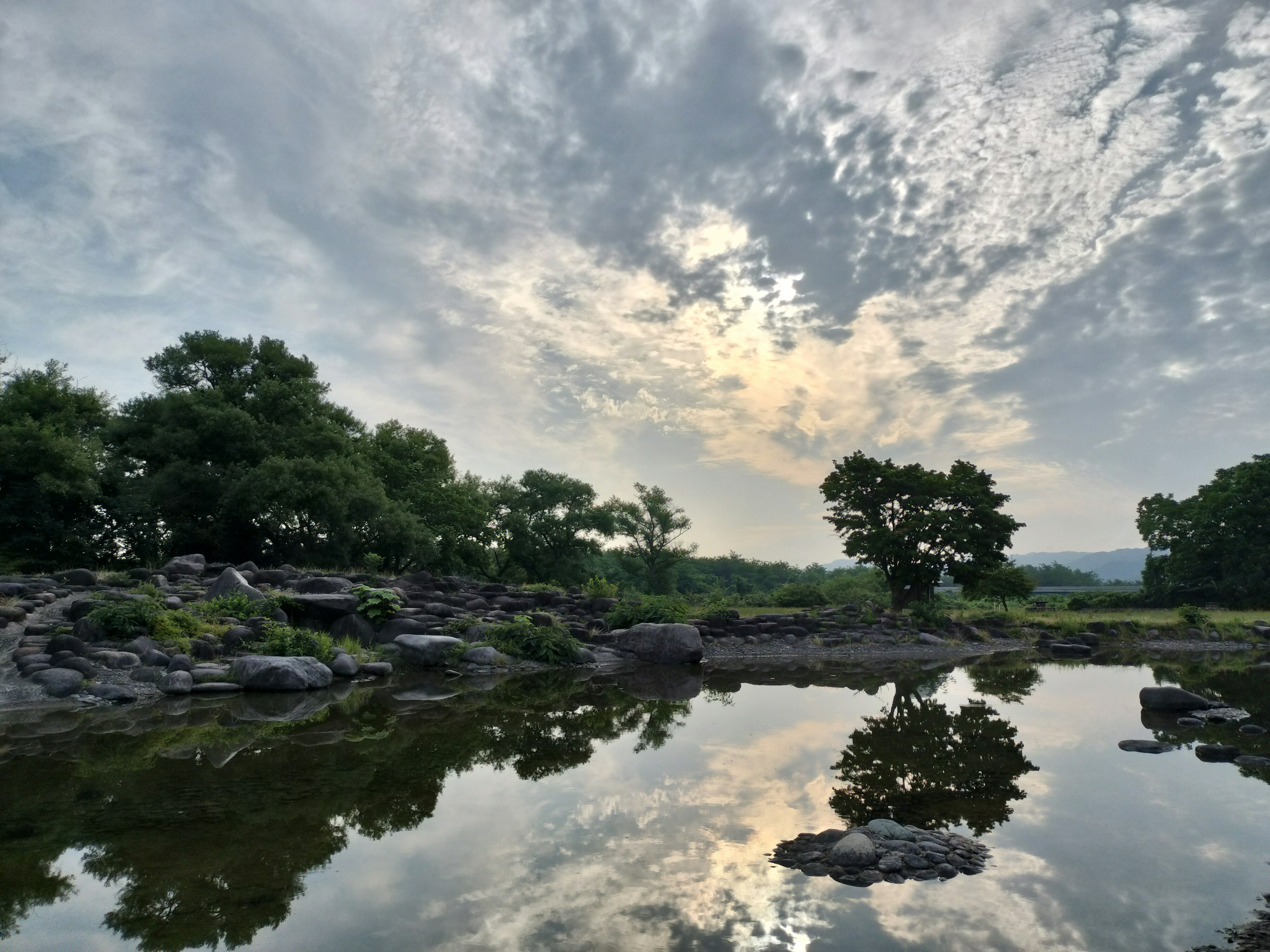 Paesaggio tranquillo con alberi e nuvole riflessi nell'acqua ferma