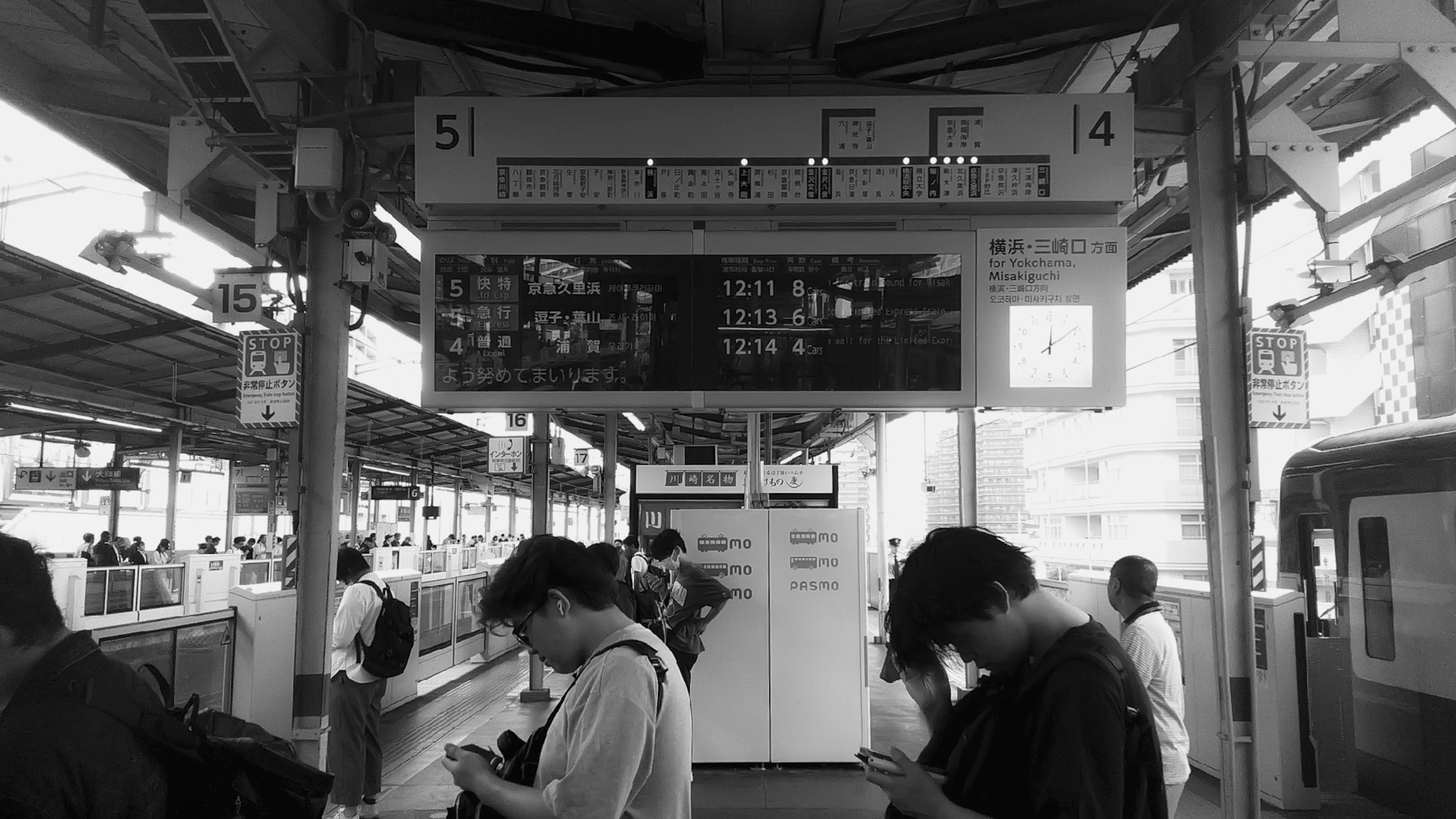 Personas esperando en una plataforma de tren con un tablero de información