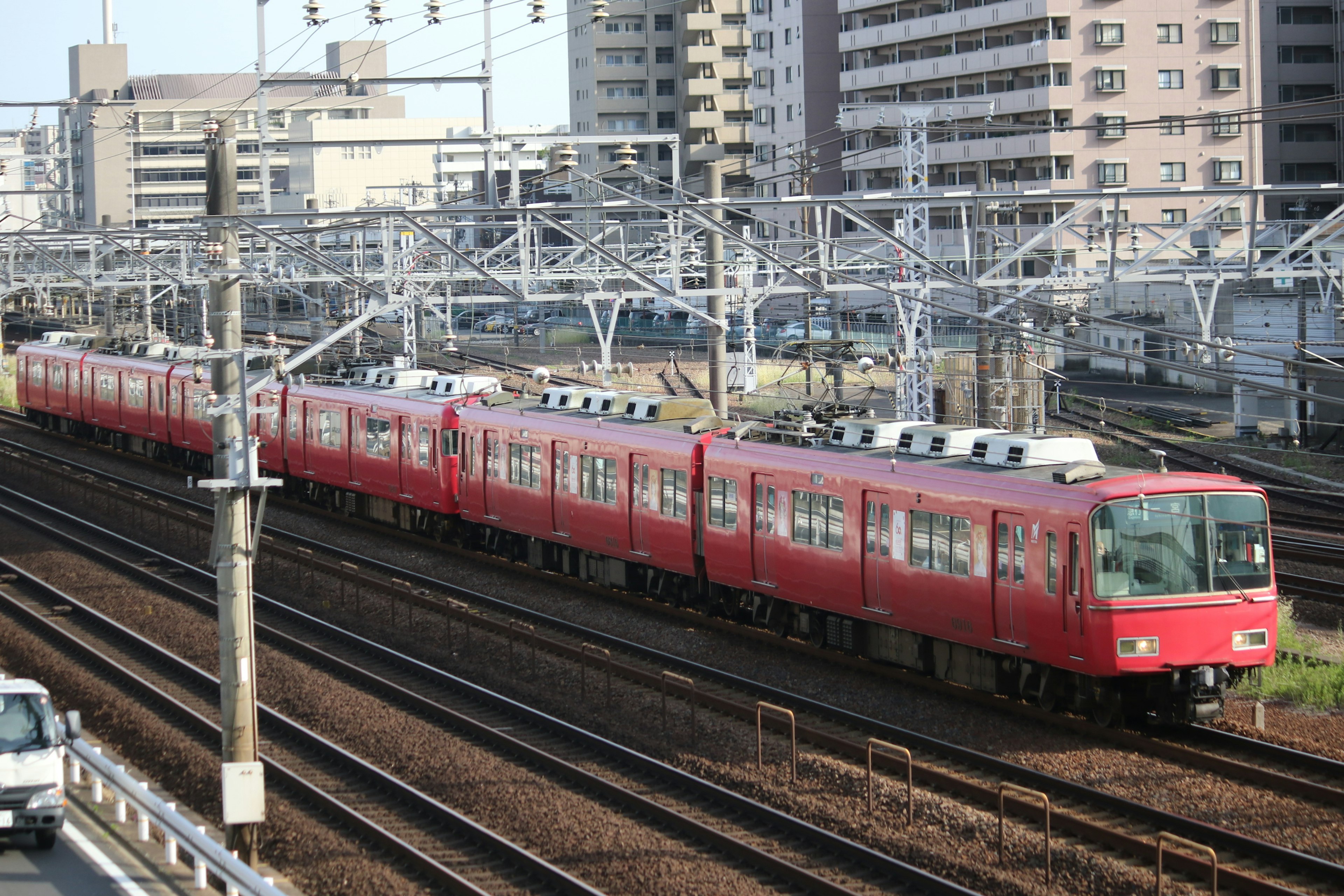 A red train running on tracks with buildings in the background