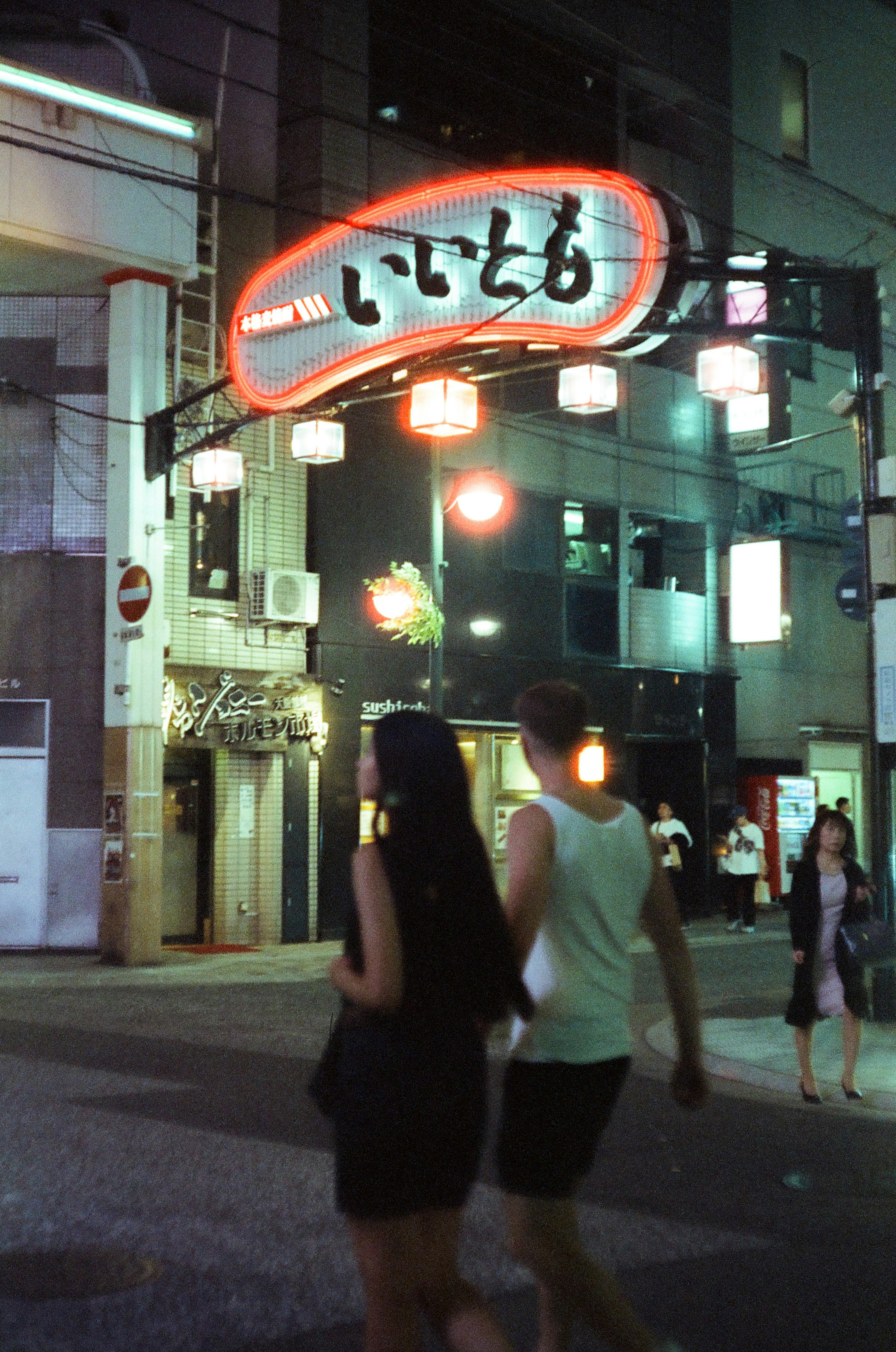 夜の街を歩くカップルといきとりの看板