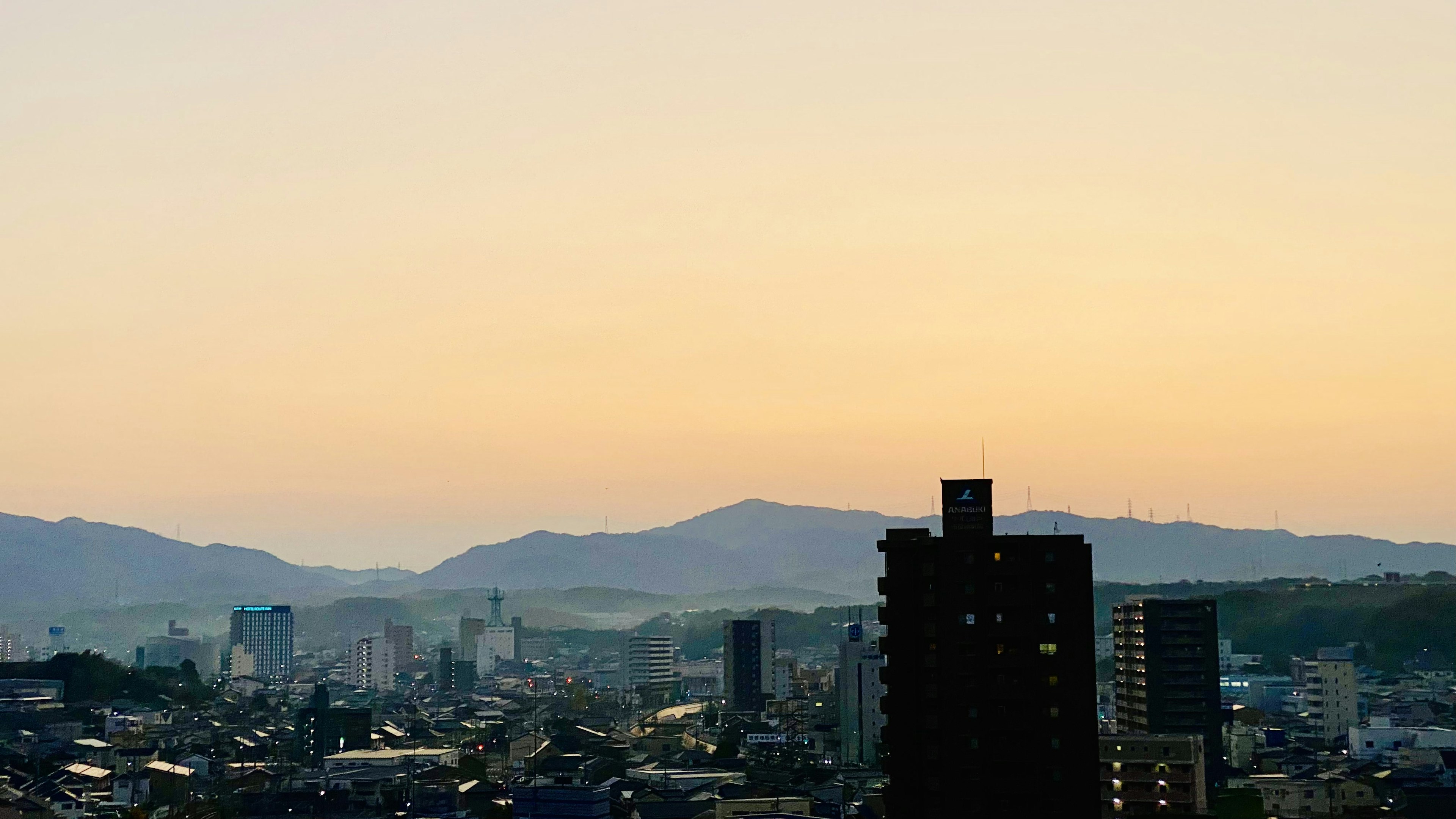 Paisaje urbano al atardecer con montañas al fondo