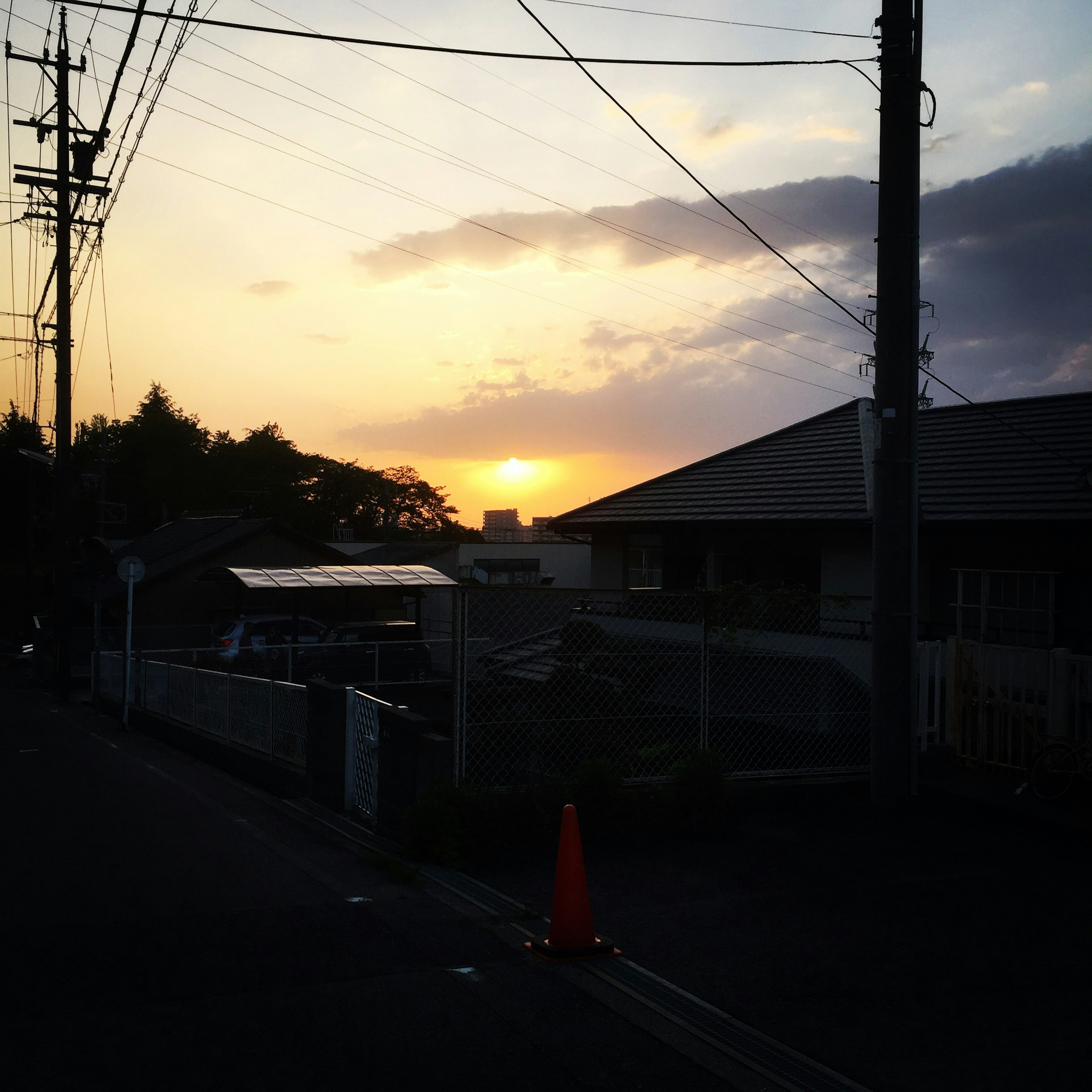 Atardecer sobre un área residencial con postes eléctricos en silueta