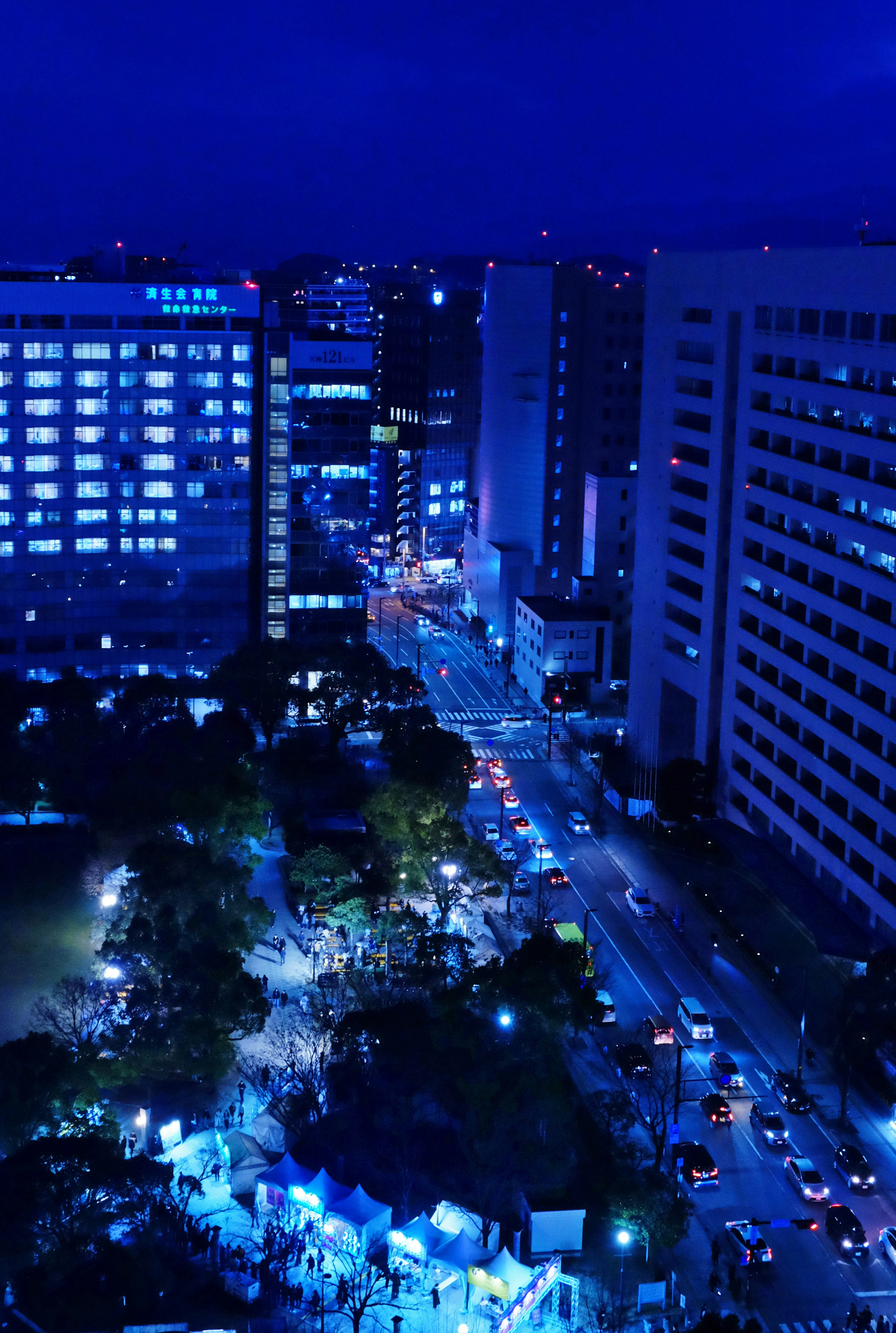 Pemandangan kota malam hari dengan gedung pencakar langit dan jalan yang diterangi lampu neon