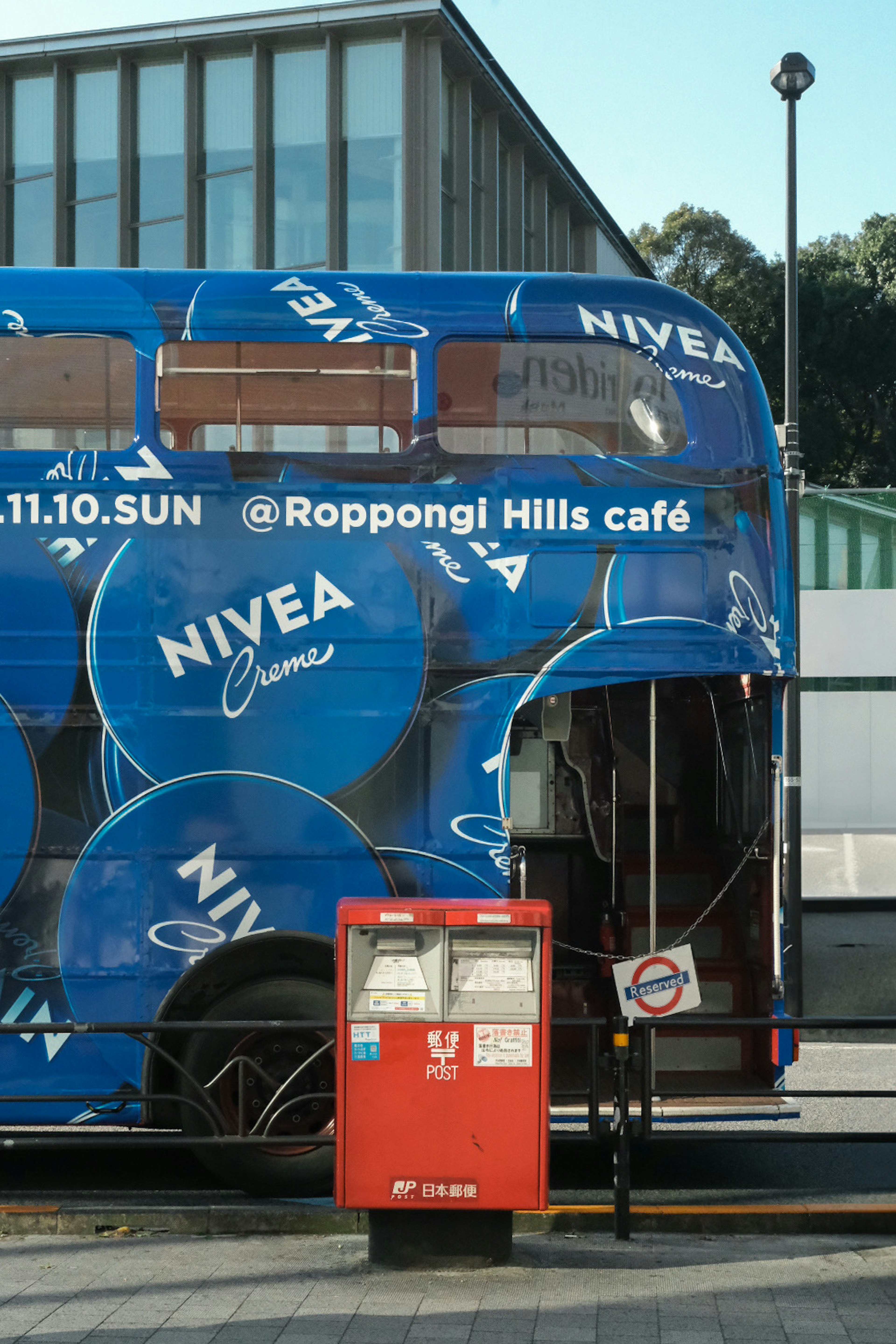 Autobus blu avvolto in una pubblicità NIVEA vicino al caffè Roppongi Hills