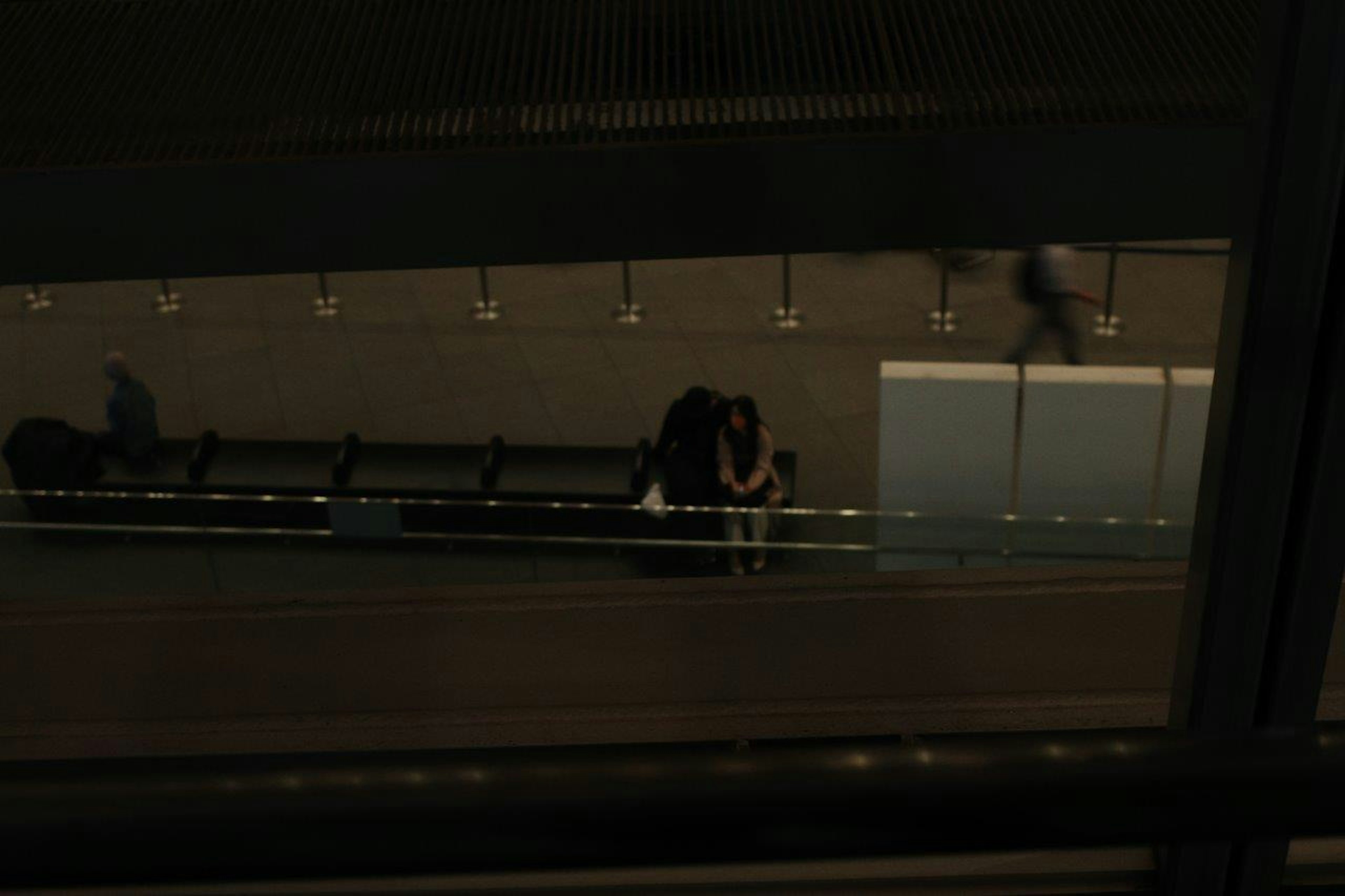 Una joven pareja abrazándose en una plataforma de tren concurrida con personas caminando