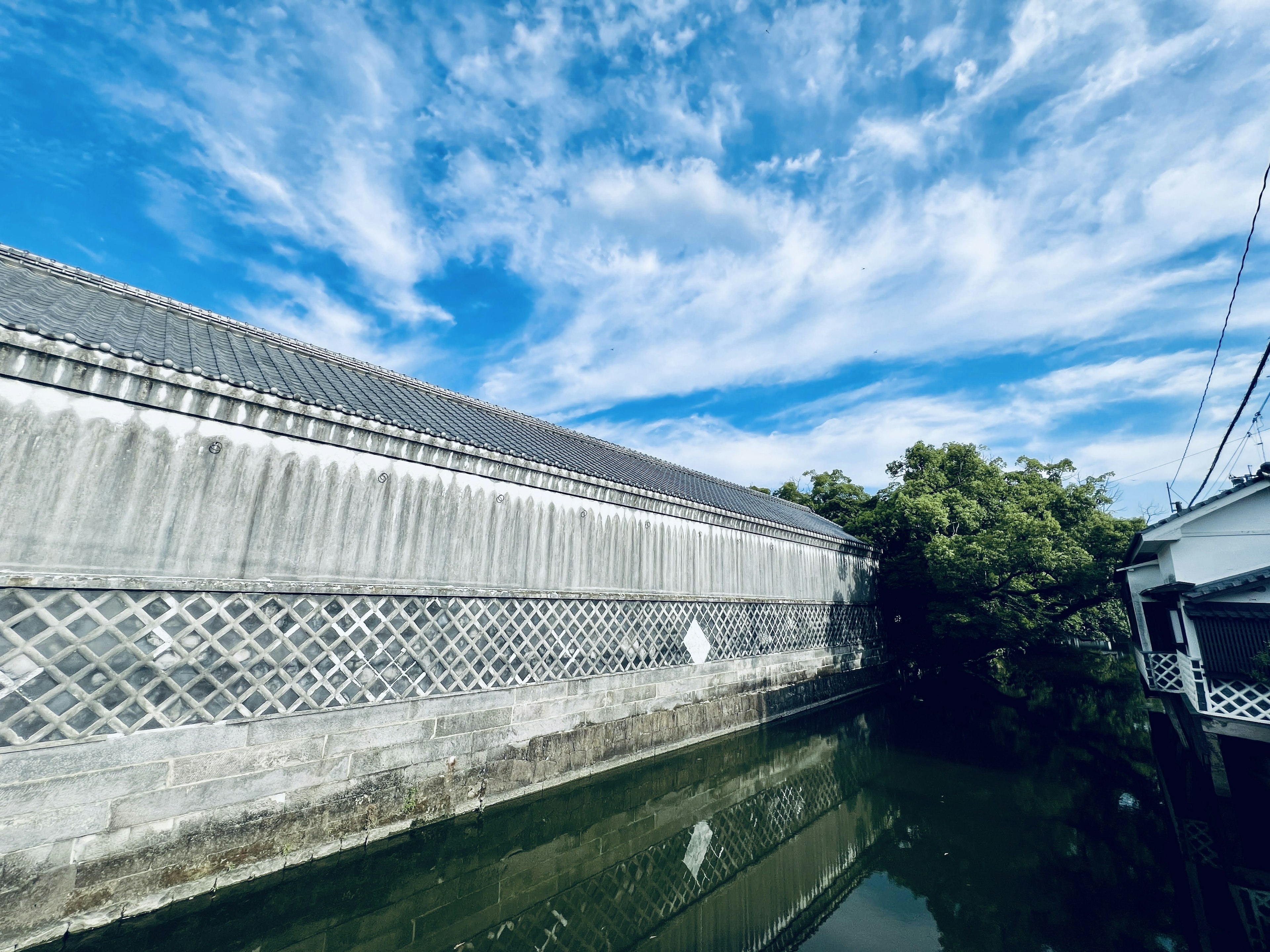 A view of an old building beside a waterway under a blue sky with white clouds