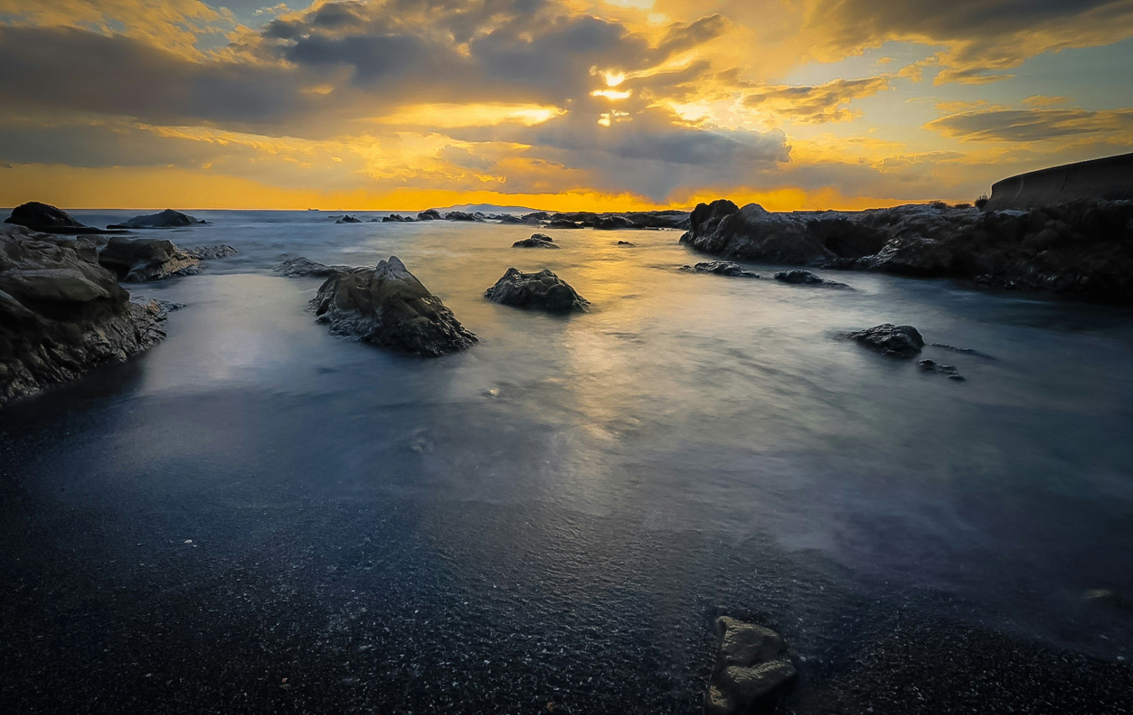 Rocky shoreline at sunset with calm waters