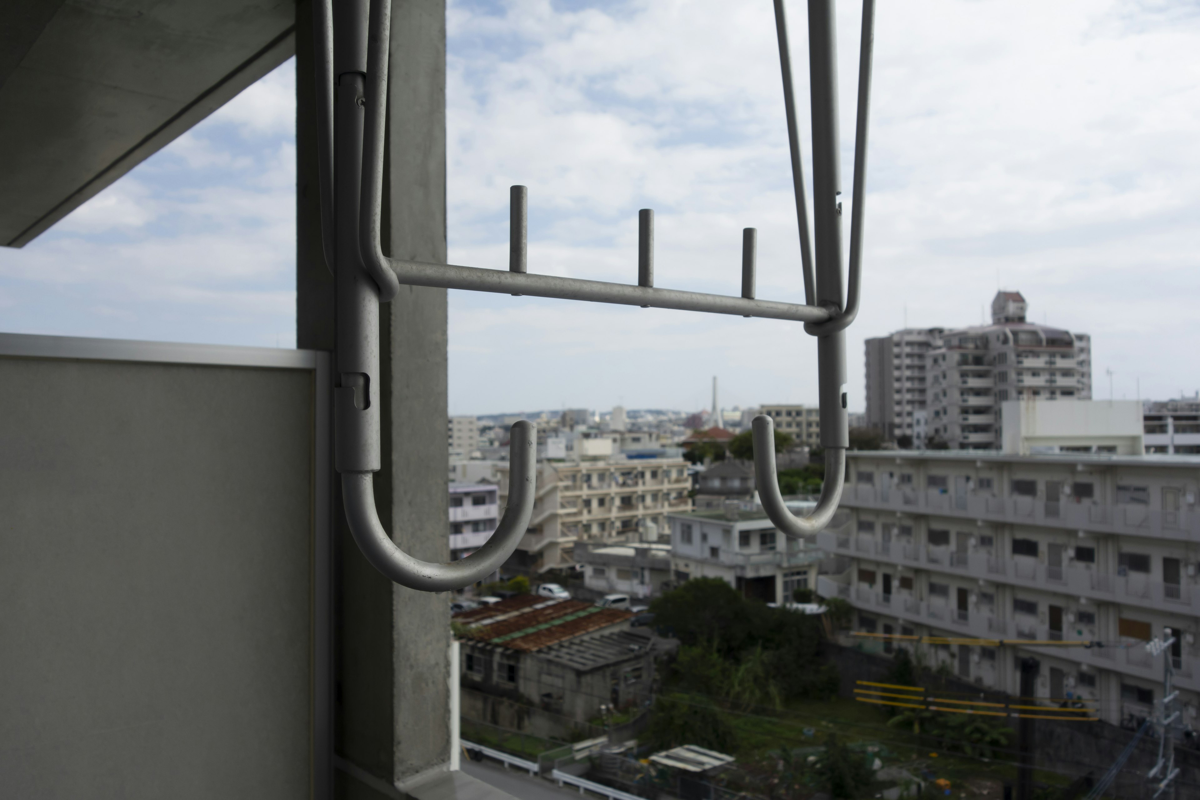 Soporte de secado de metal fijado a la barandilla del balcón con edificios circundantes