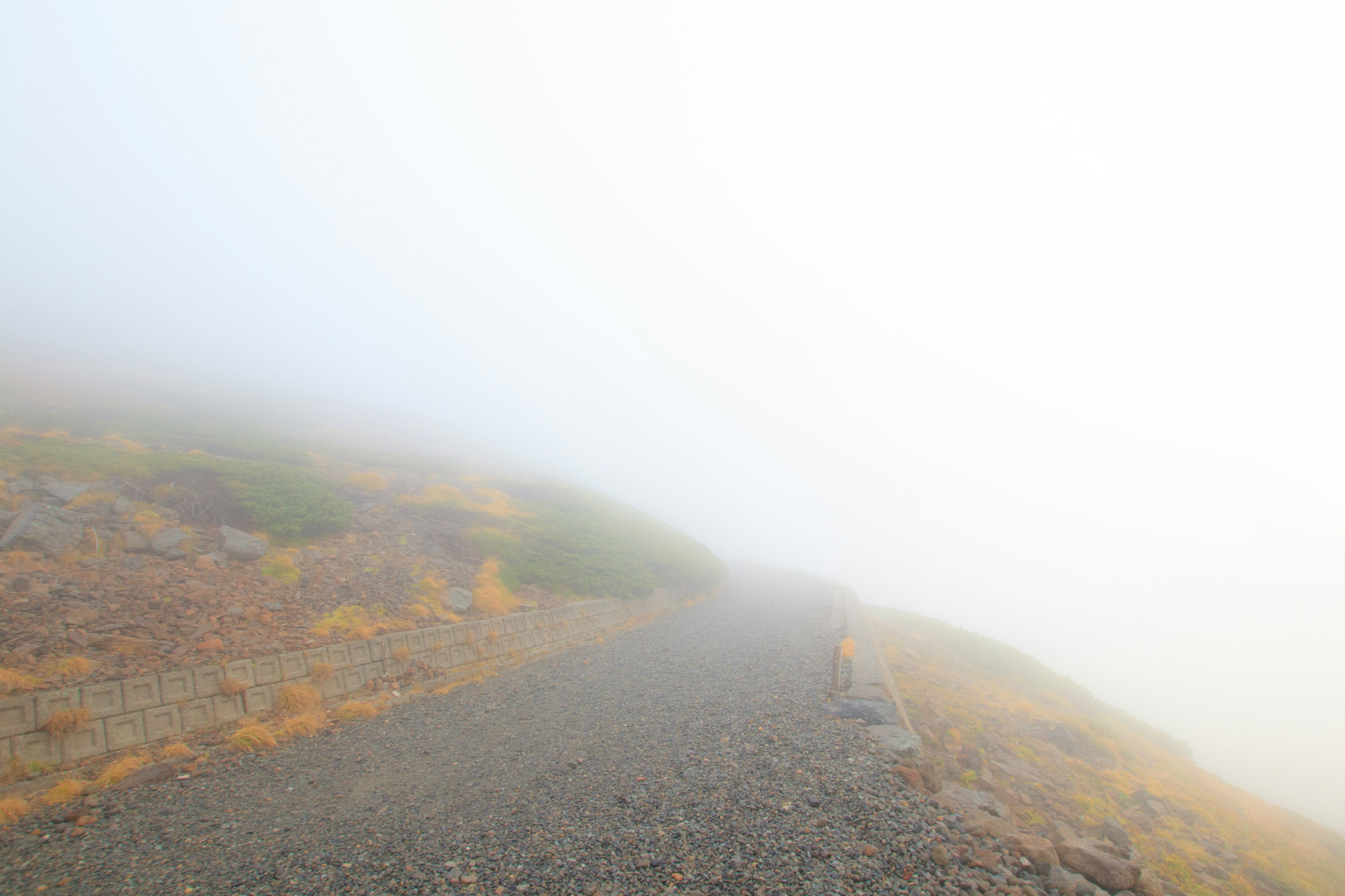 Chemin de montagne couvert de brouillard avec des gravillons