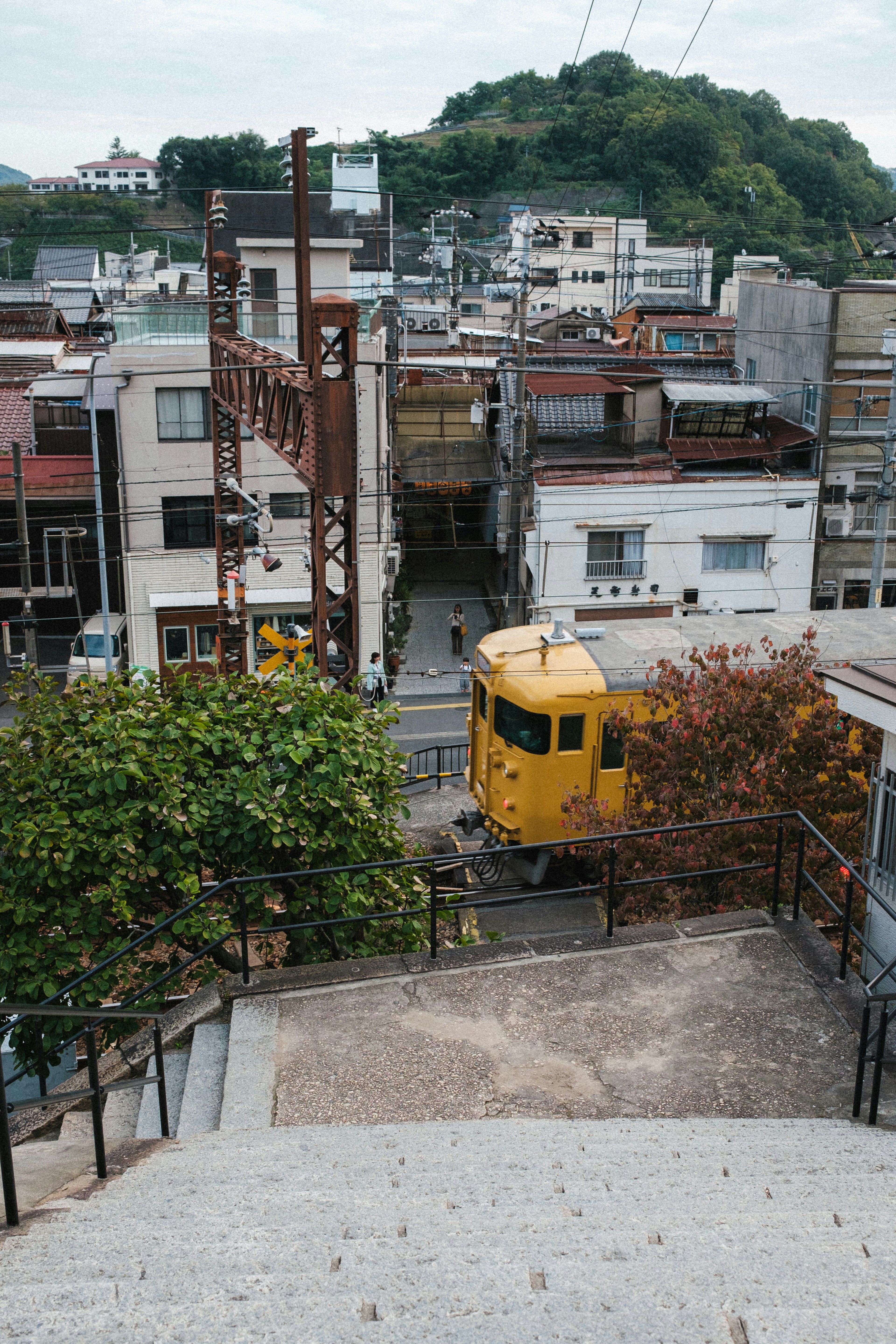 階段を下から見上げた景色に黄色い列車と住宅街が広がる