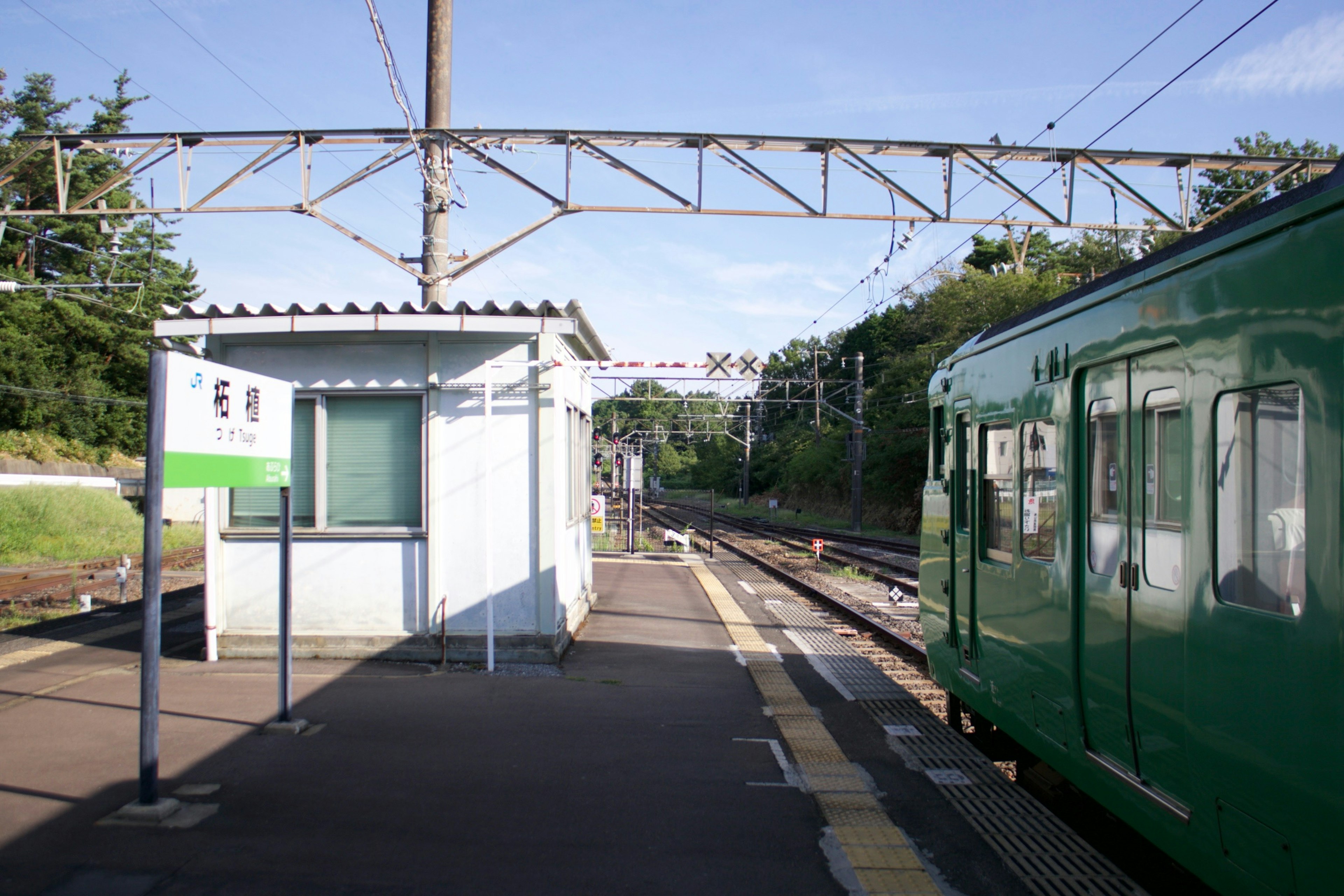 A green train at a train station with a building and tracks visible