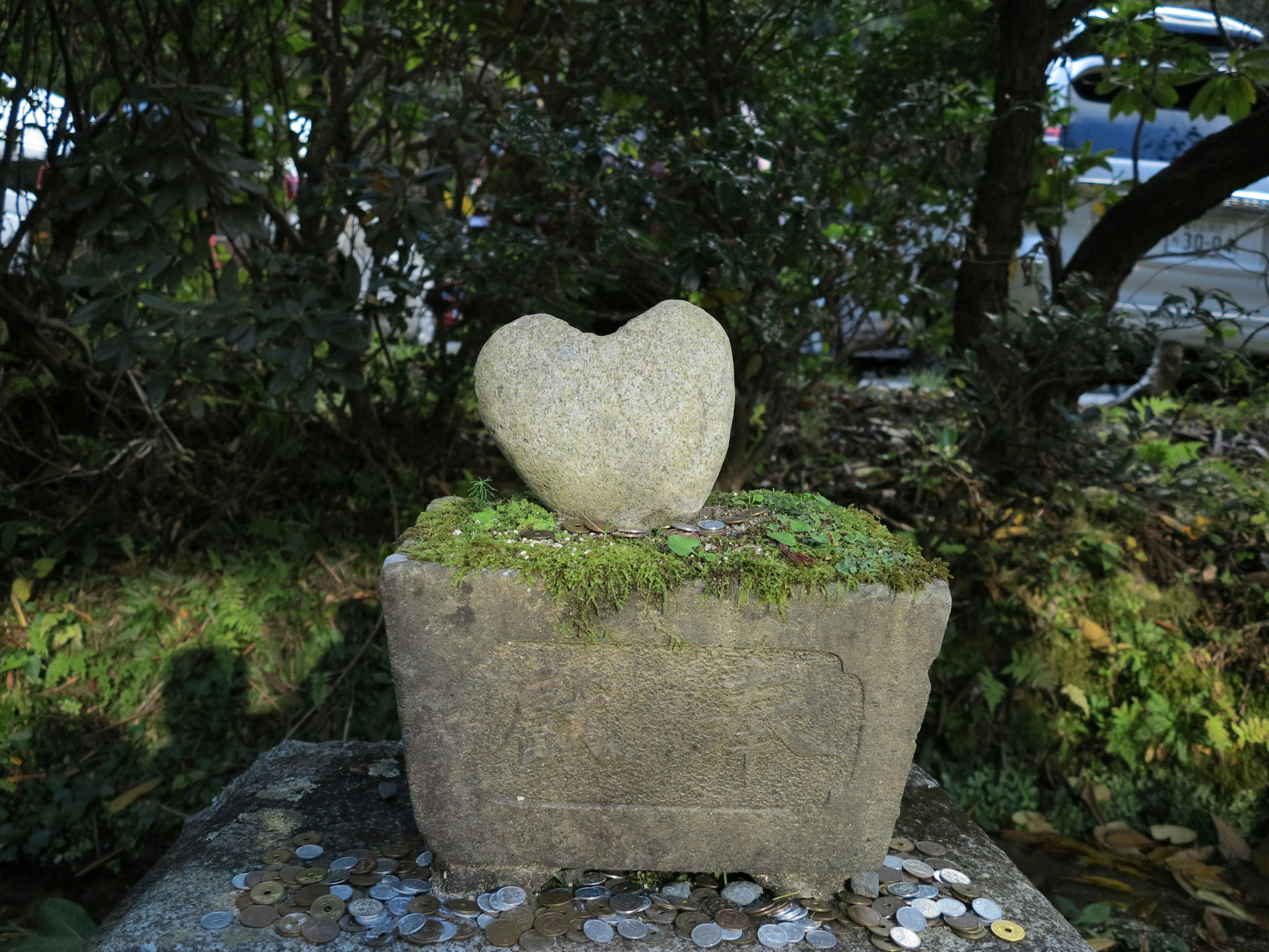 心形の石が苔の生えた台座の上にある風景