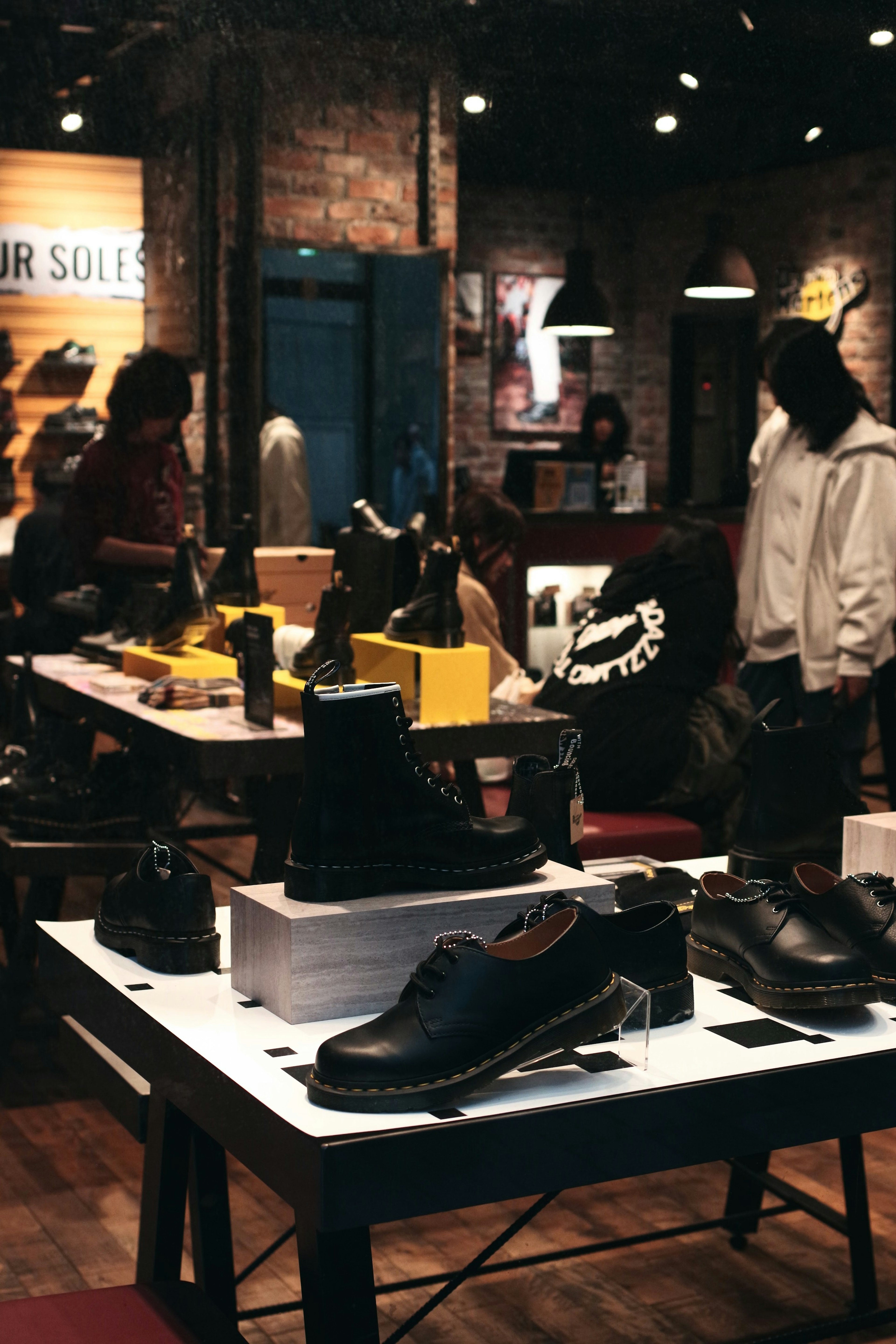 Vista interior de una tienda de zapatos con varios modelos y clientes