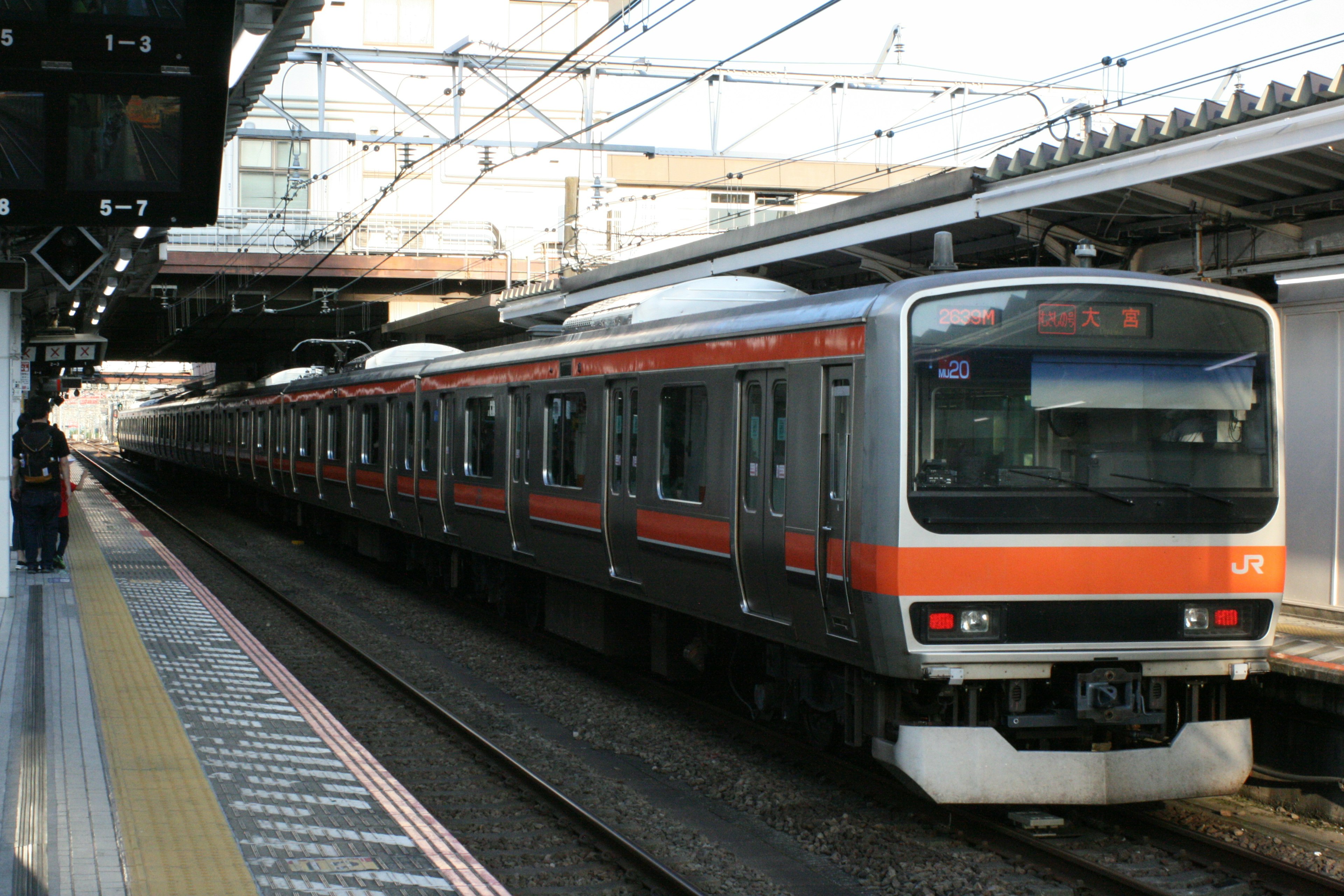 オレンジのストライプが入った日本の電車が駅に停車している