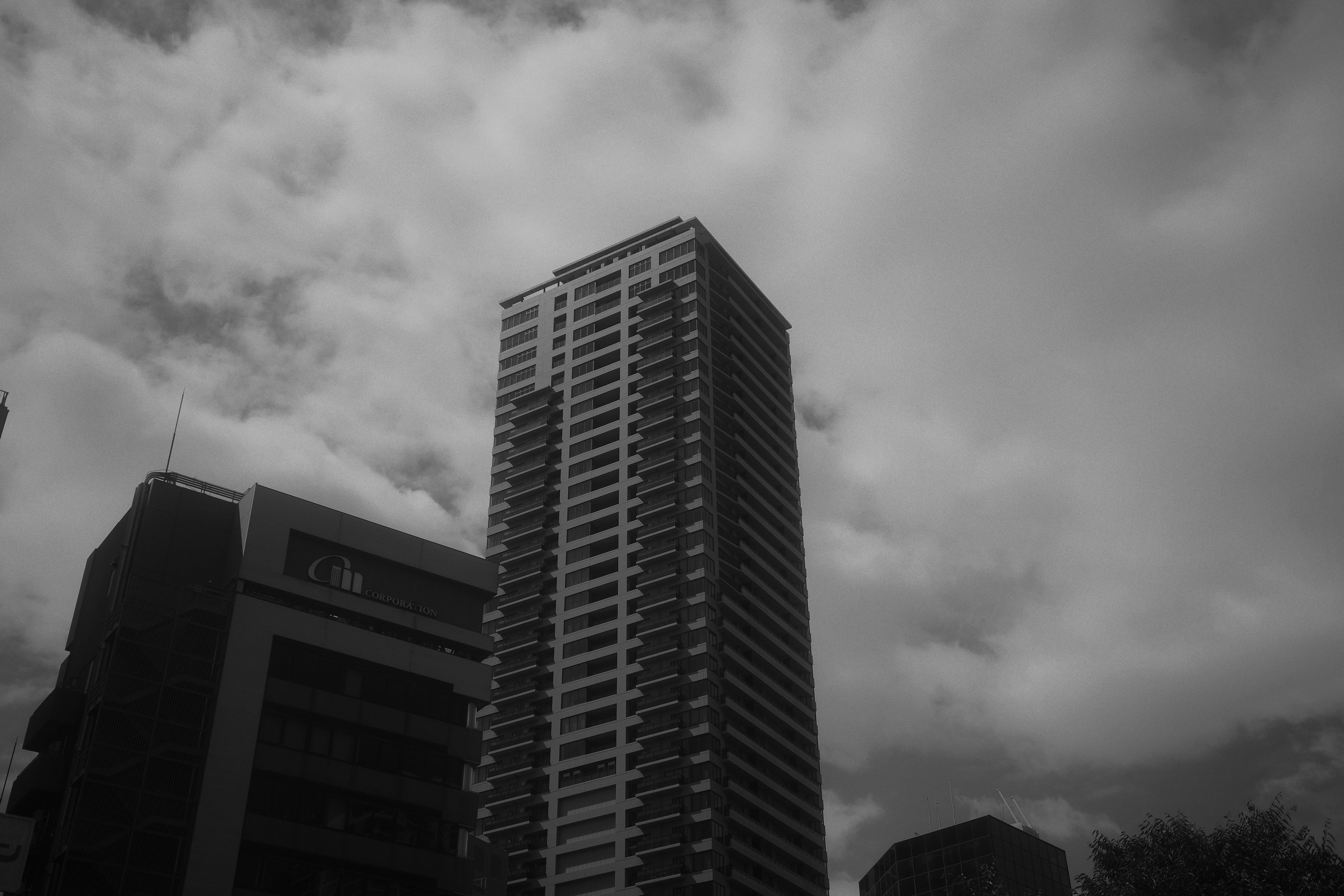 Black and white image of a tall building against a cloudy sky